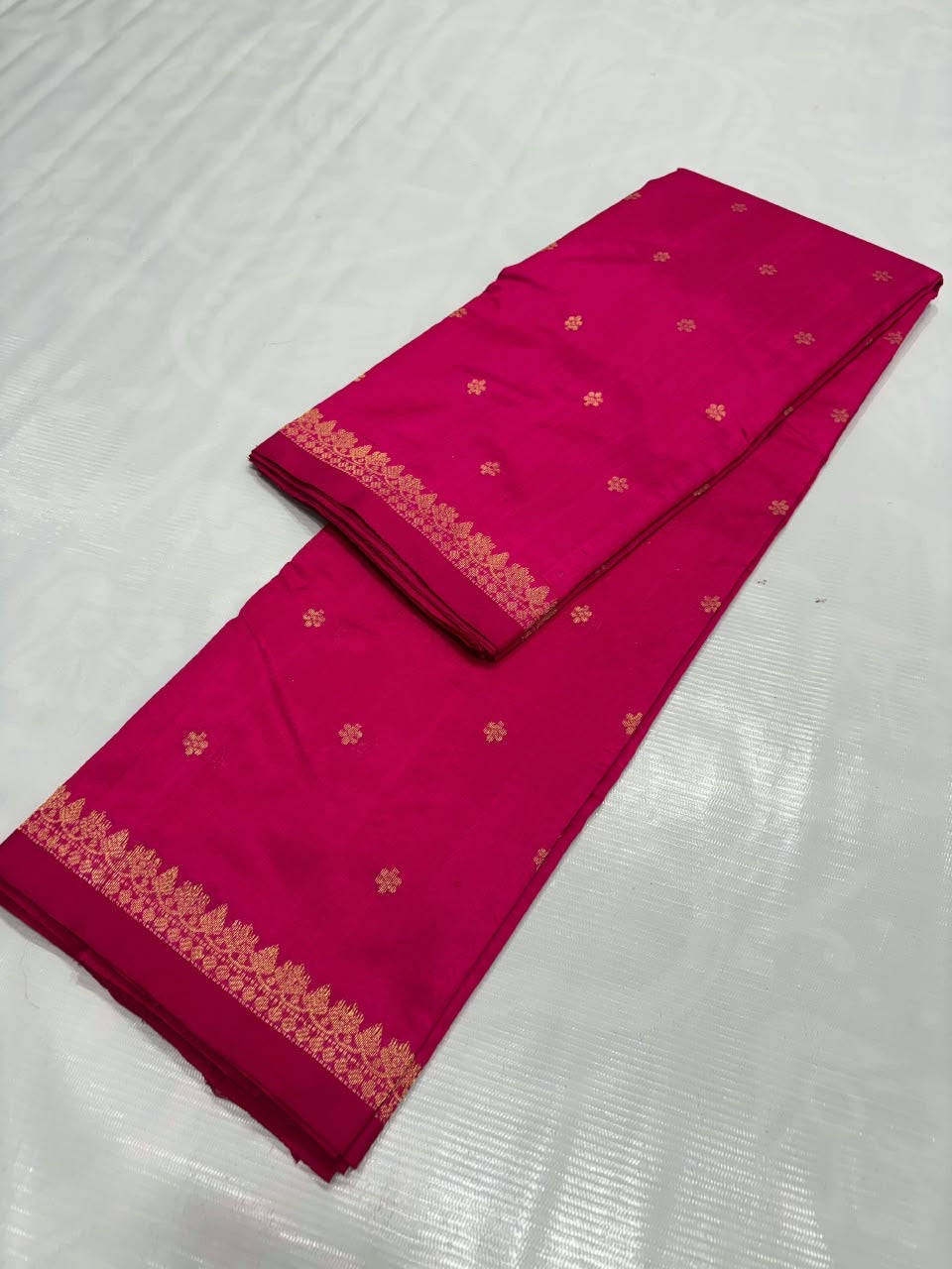 Close-up of gold-toned floral accents on rani-pink silk