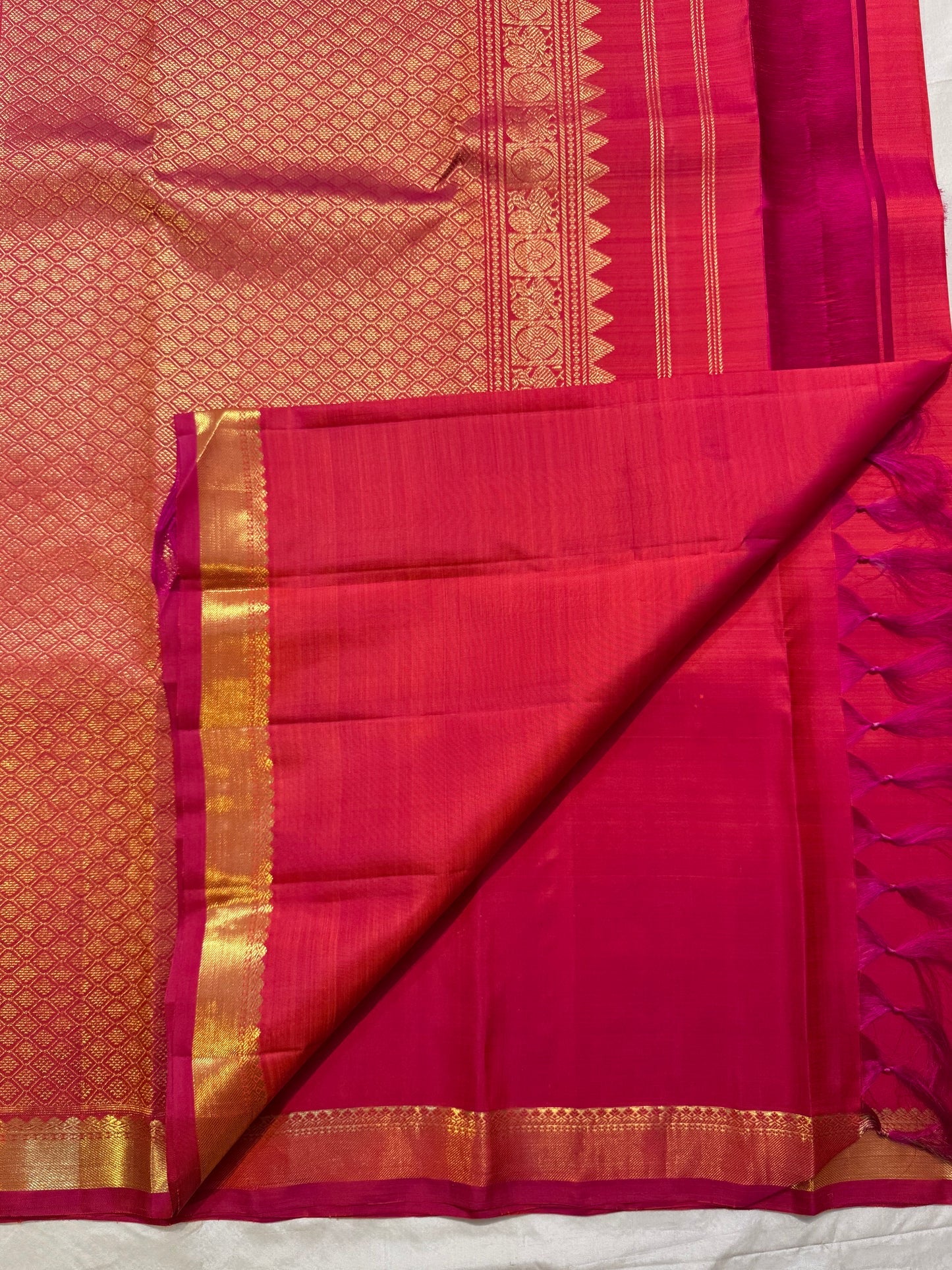 Rani Pink and coral-orange Kanjivaram saree folded with petite gold buttas and zari border