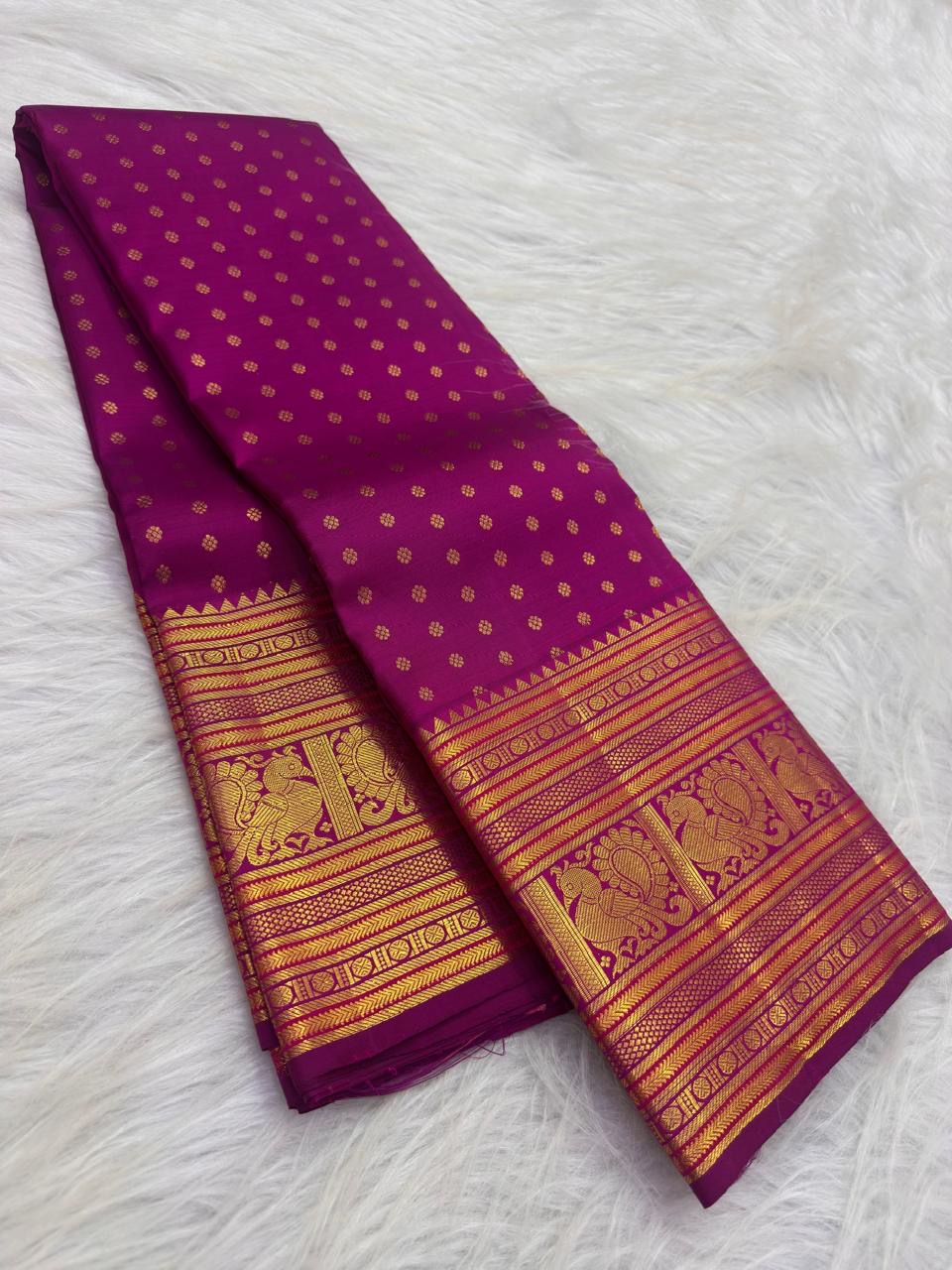 Close view of dense handwoven gold zari buttas across saturated Rani Pink pure silk body.