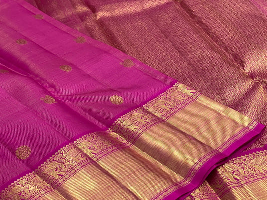 Dense gold zari pallu with repeating geometric field on saturated Rani Pink silk.