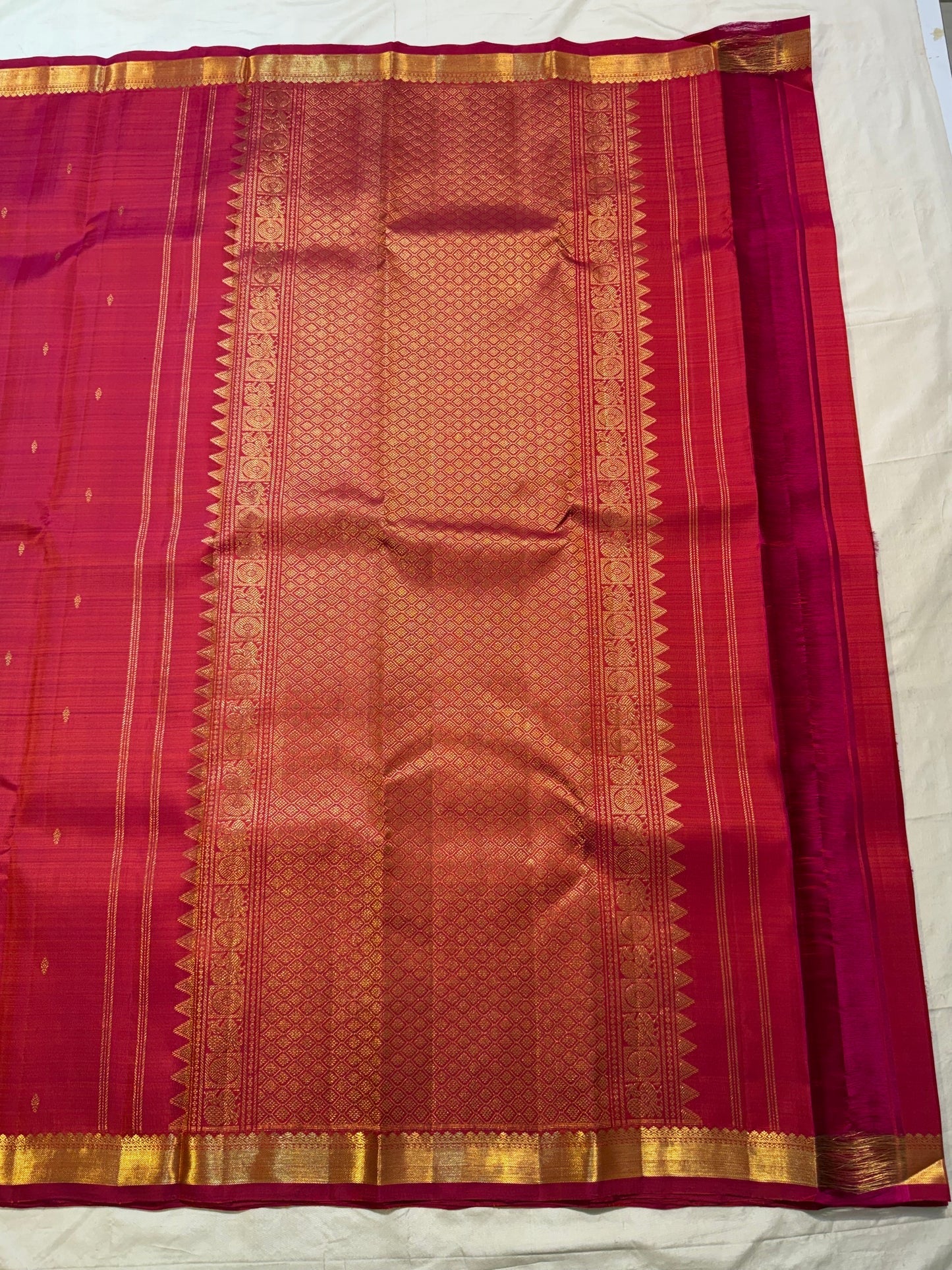 Close view of petite gold zari buttas spaced across the Rani Pink silk body
