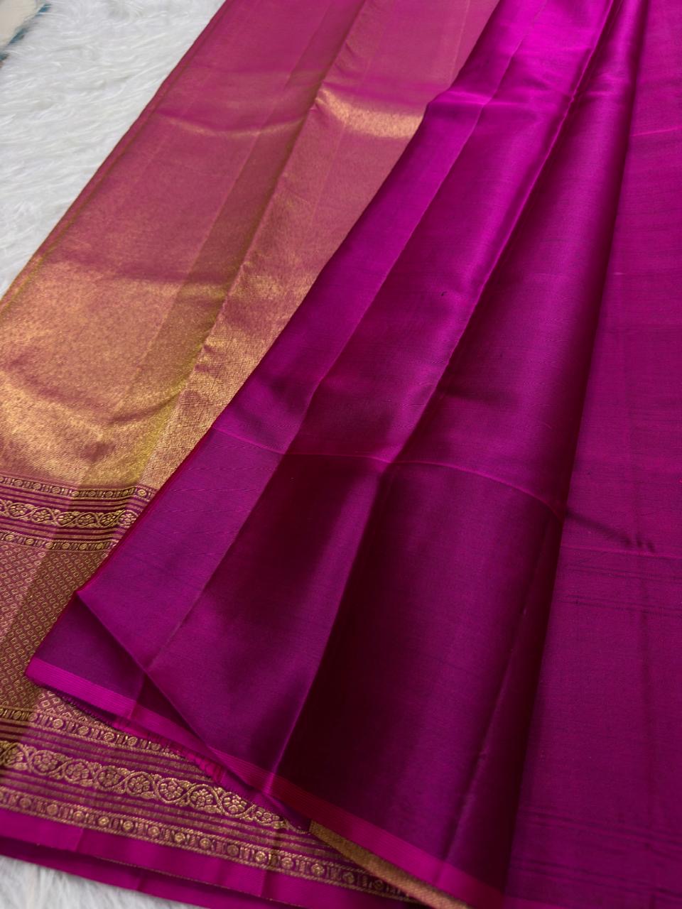 Close view of warm-gold geometric border on radiant Rani Pink Kanchipuram silk.