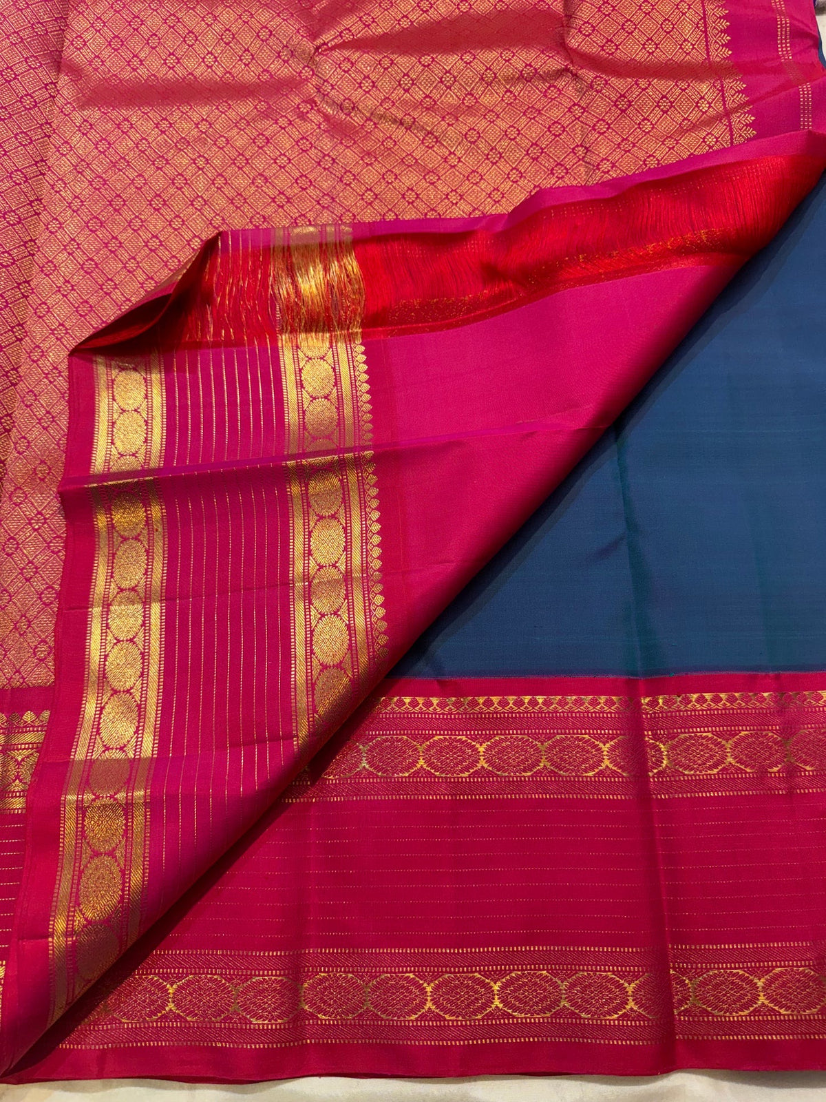 Rani Pink Korvai border with warm gold zari registers on Peacock Blue Rettapet Kanchipuram saree.