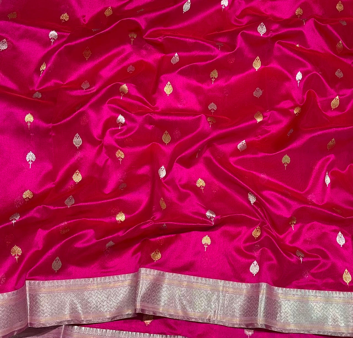 Rani Pink handloom Pattu Silk Chanderi saree folded to show scattered gold leaf buttas and broad metallic border.