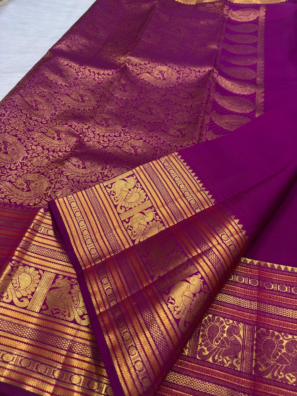 Close view of repeating handwoven peacock motifs framed within traditional gold zari border panels.