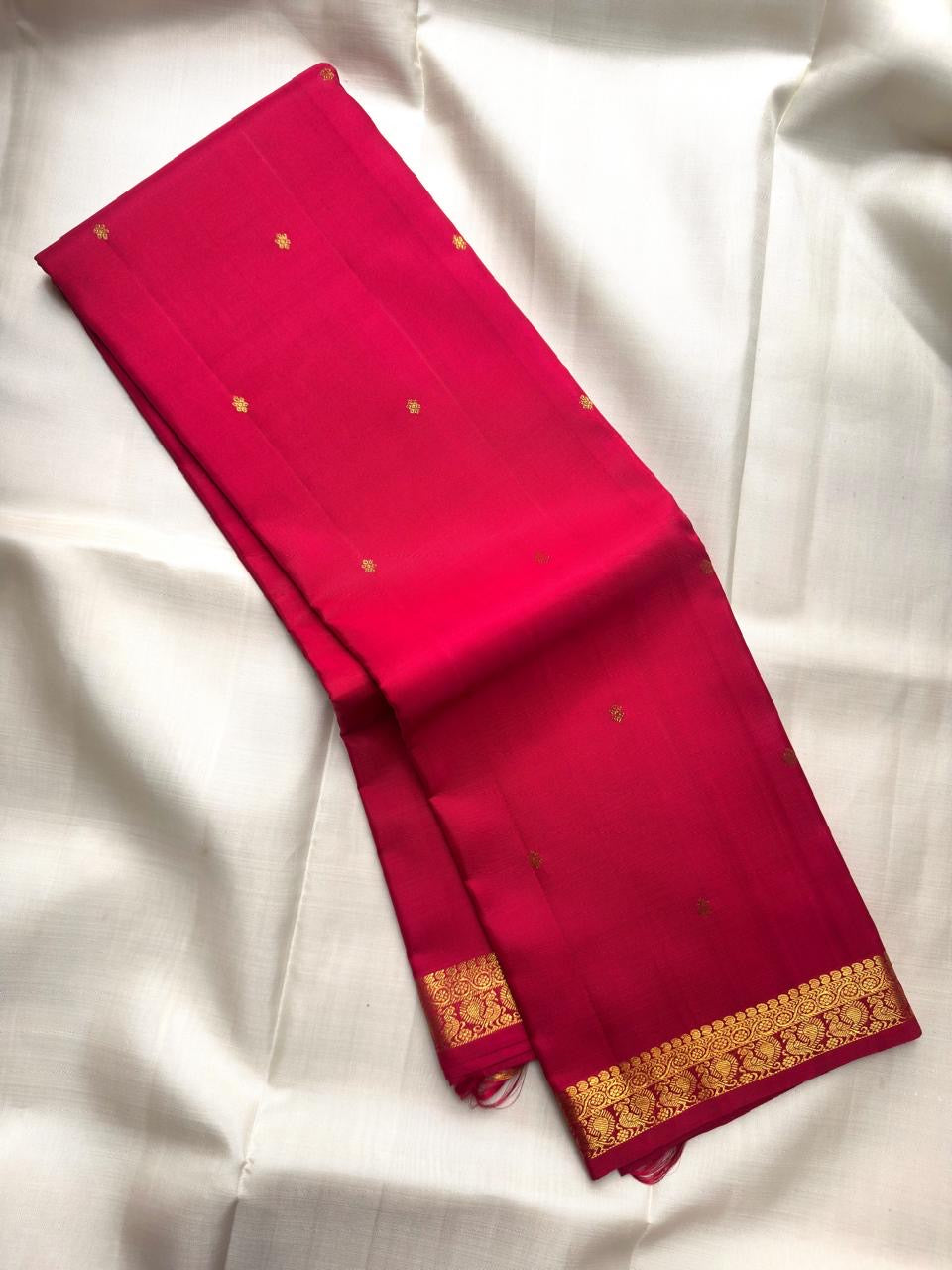 Handwoven Pure Silk Kancheepuram Butta saree with an open red body and small gold zari motifs.