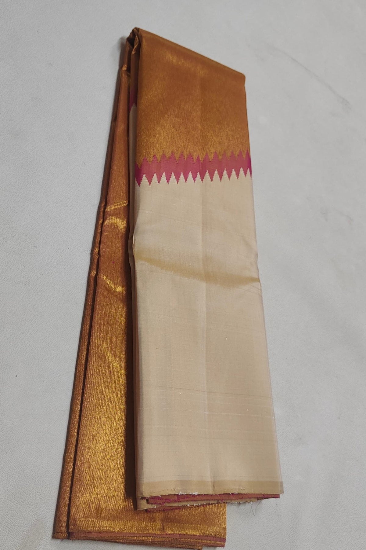 Antique-gold zari border with Rani Pink temple-style transition on ivory Kanjivaram silk.