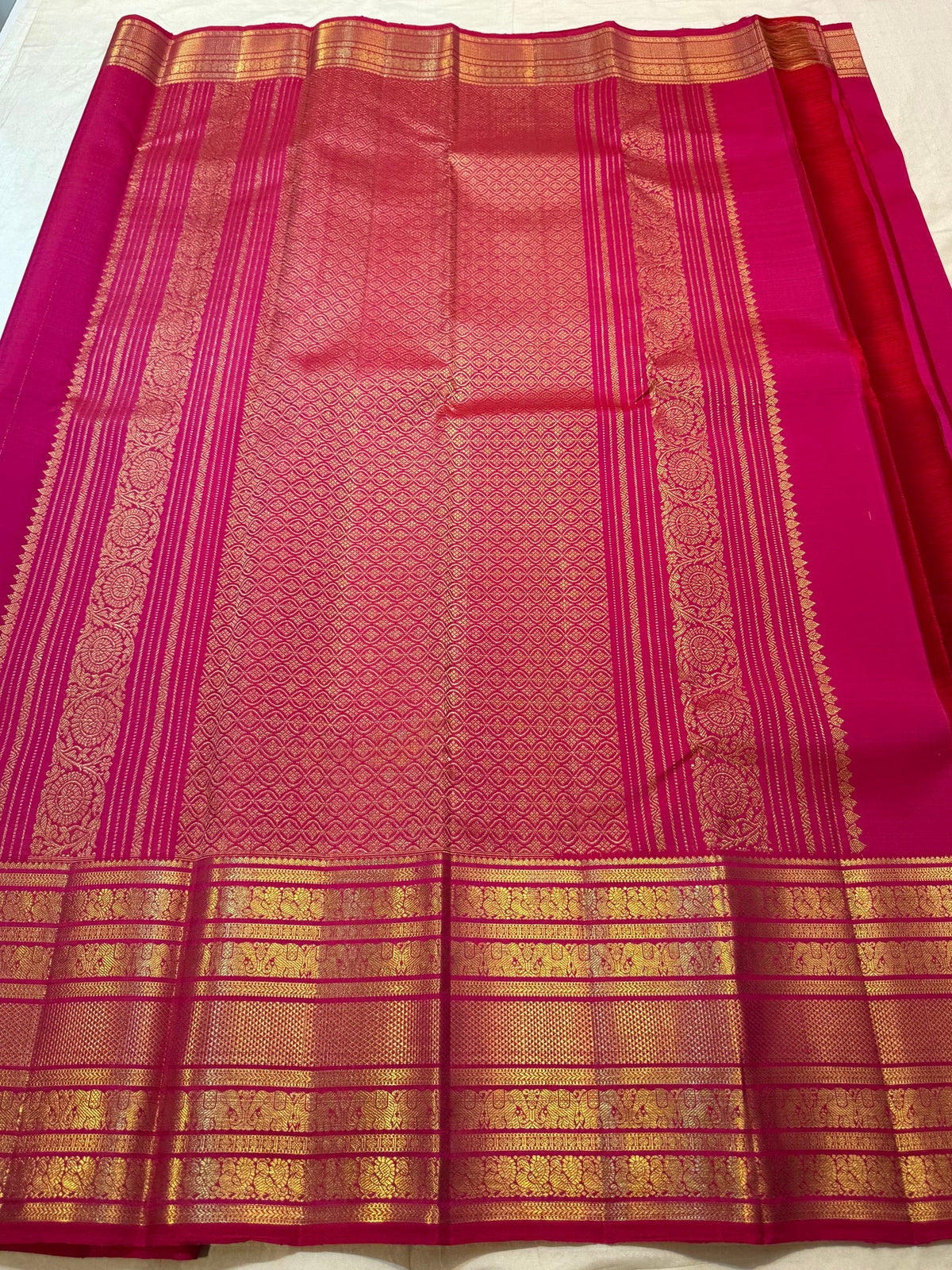 Rani Pink pure silk Kanjivaram Varisaipet saree with spaced antique-gold zari buttas and layered gold border.