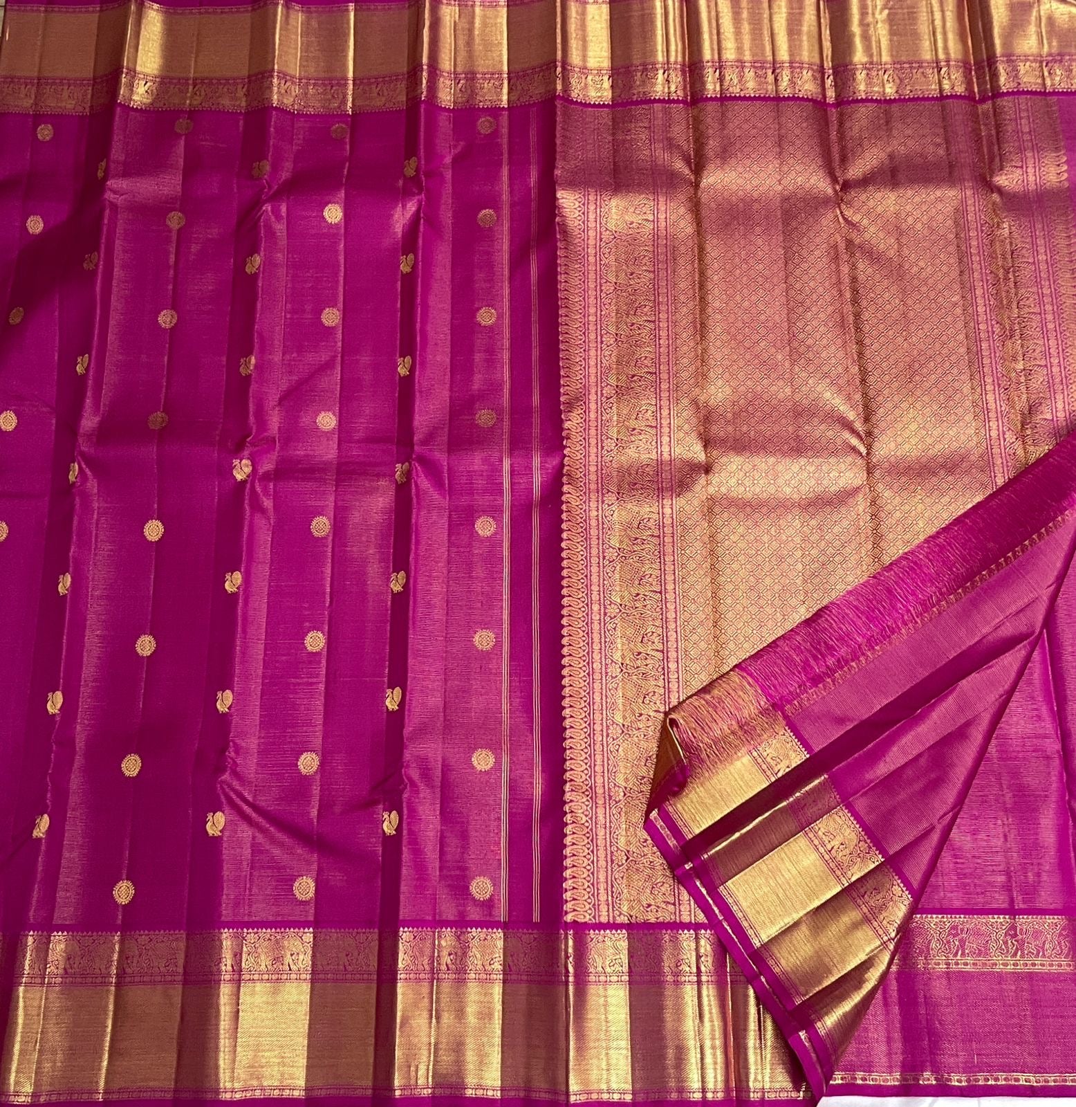 Compact ornamental gold zari butta against the luminous Rani Pink silk surface.