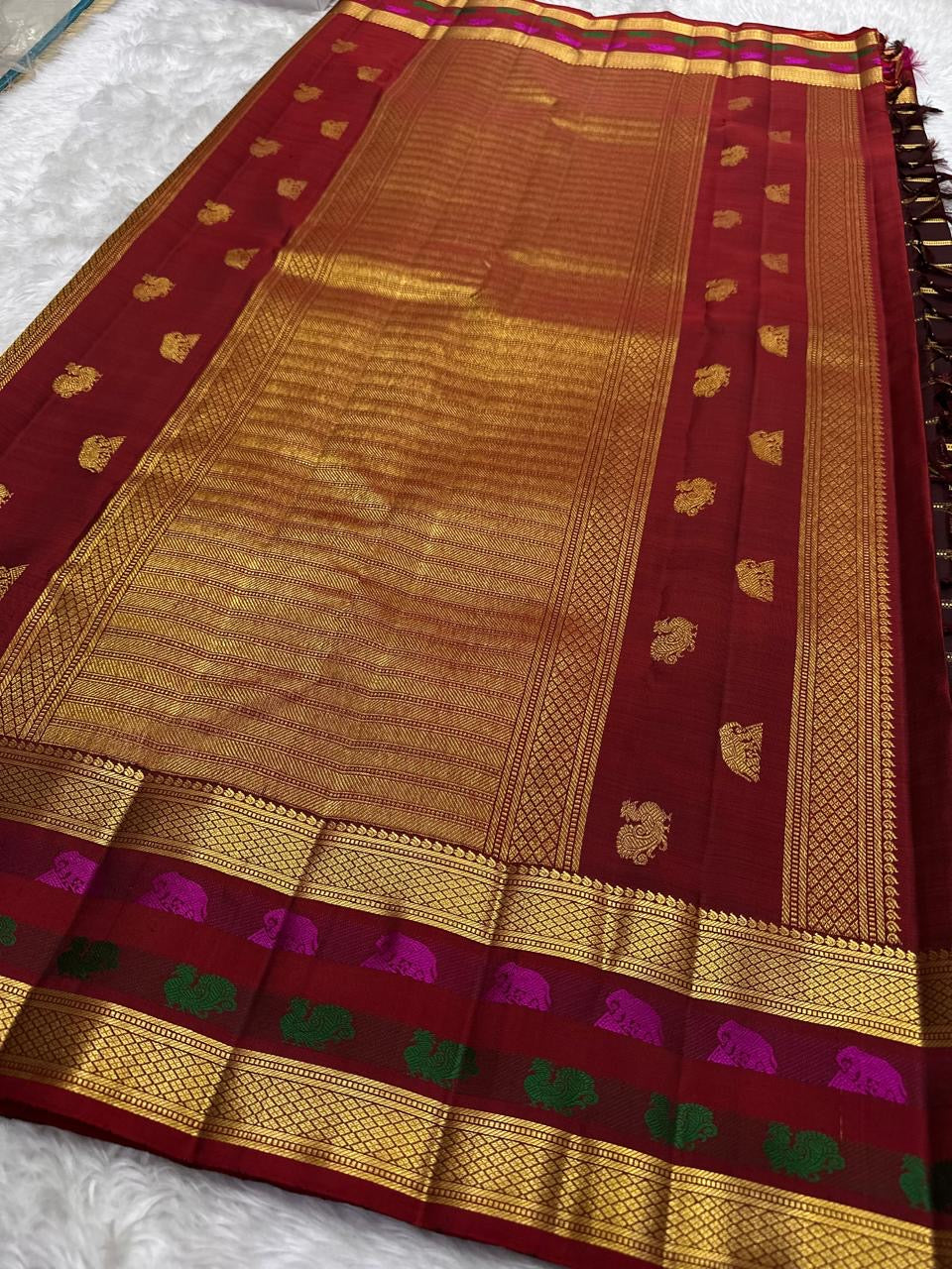 Close detail of Rani Pink Yaanai and saturated green bird-inspired motifs against classic gold zari.