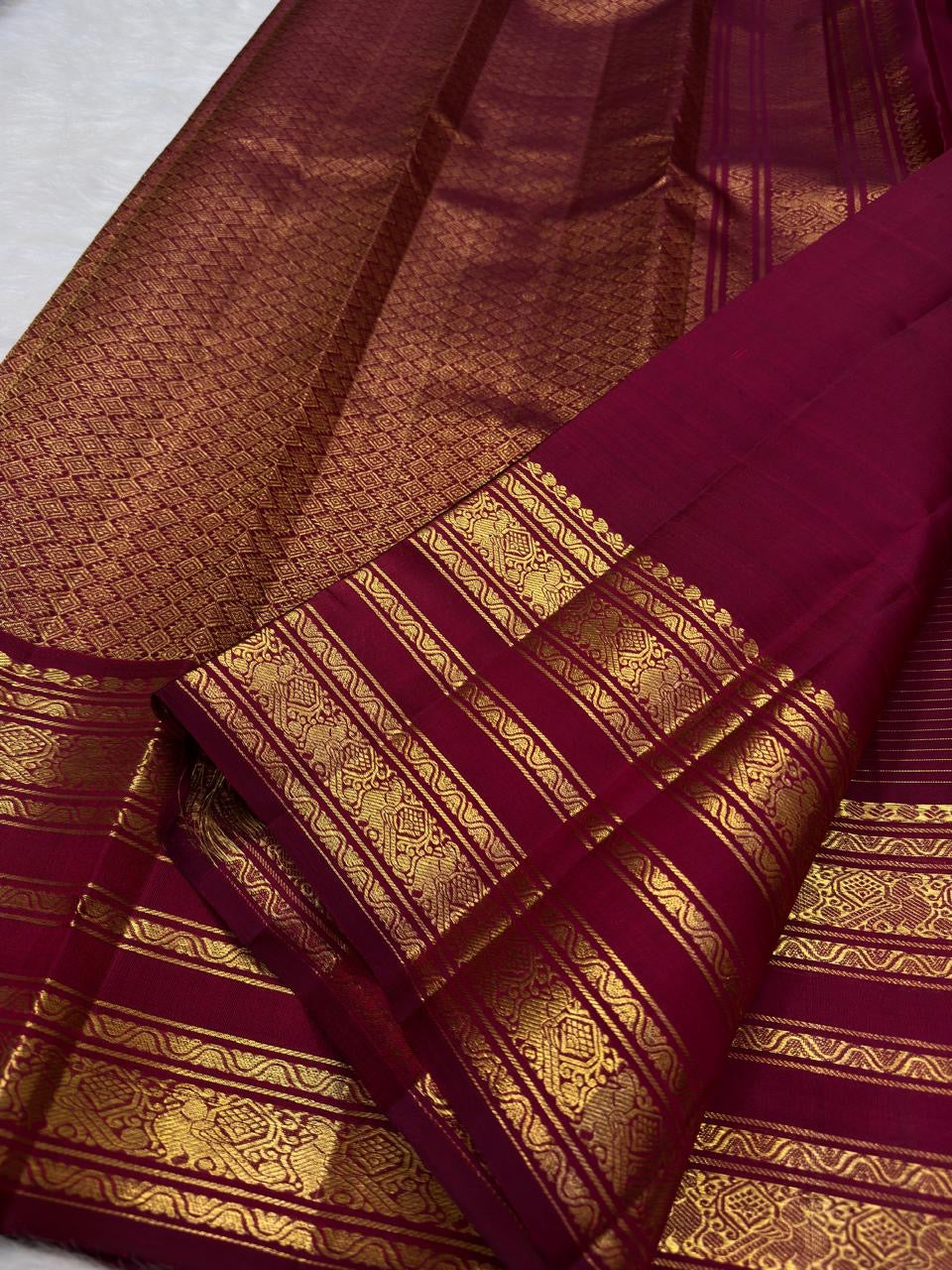 Raspberry maroon Kanchipuram silk saree with fine gold checked texture and layered Varisaipet border.