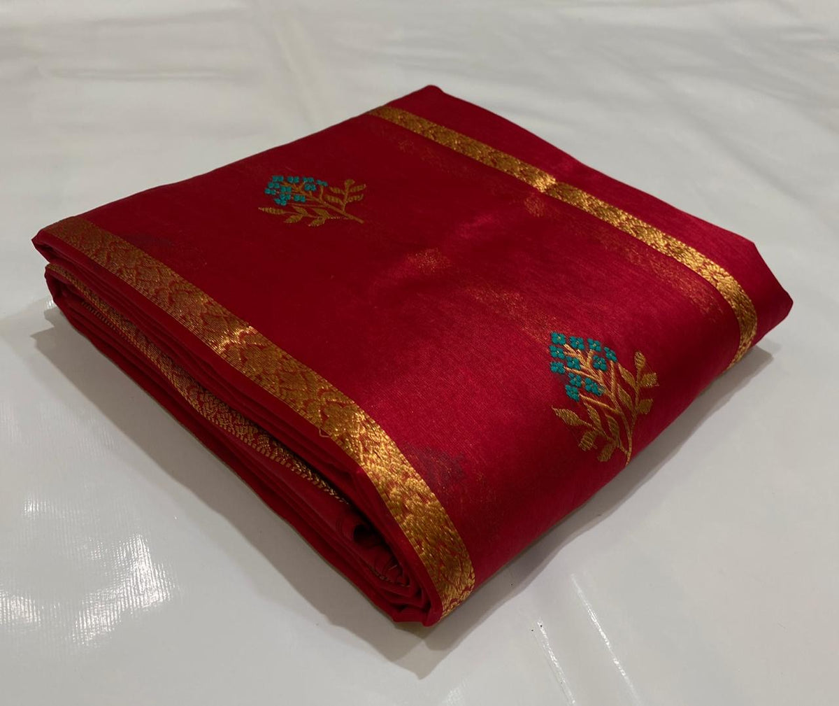 Full raspberry red Pattu Silk Chanderi saree with vertical gold zari lines and turquoise-and-gold floral woven accents