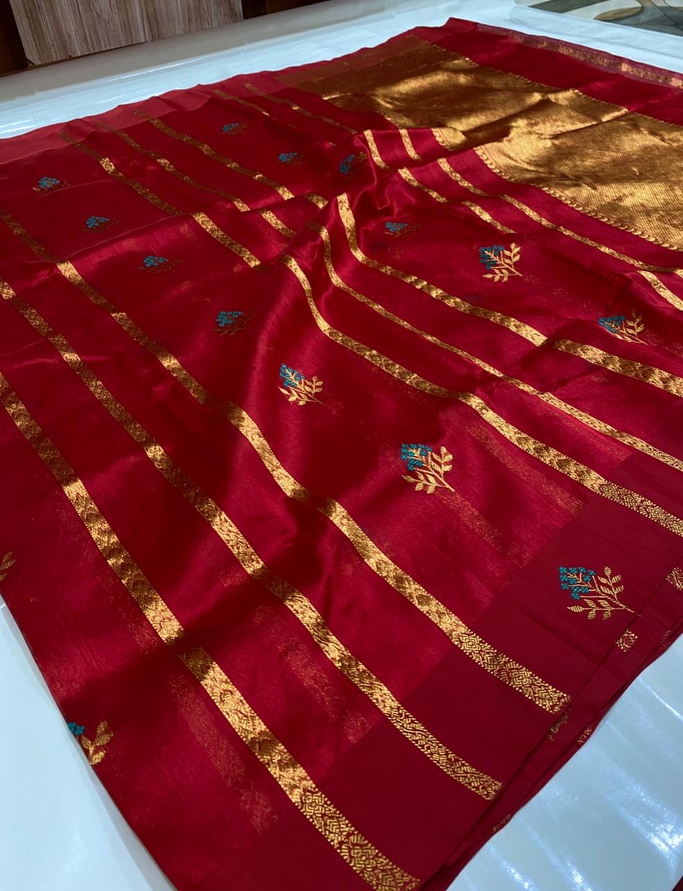 Raspberry red Chanderi silk saree showing gold-toned zari stripes, turquoise floral buttas and luminous woven pallu