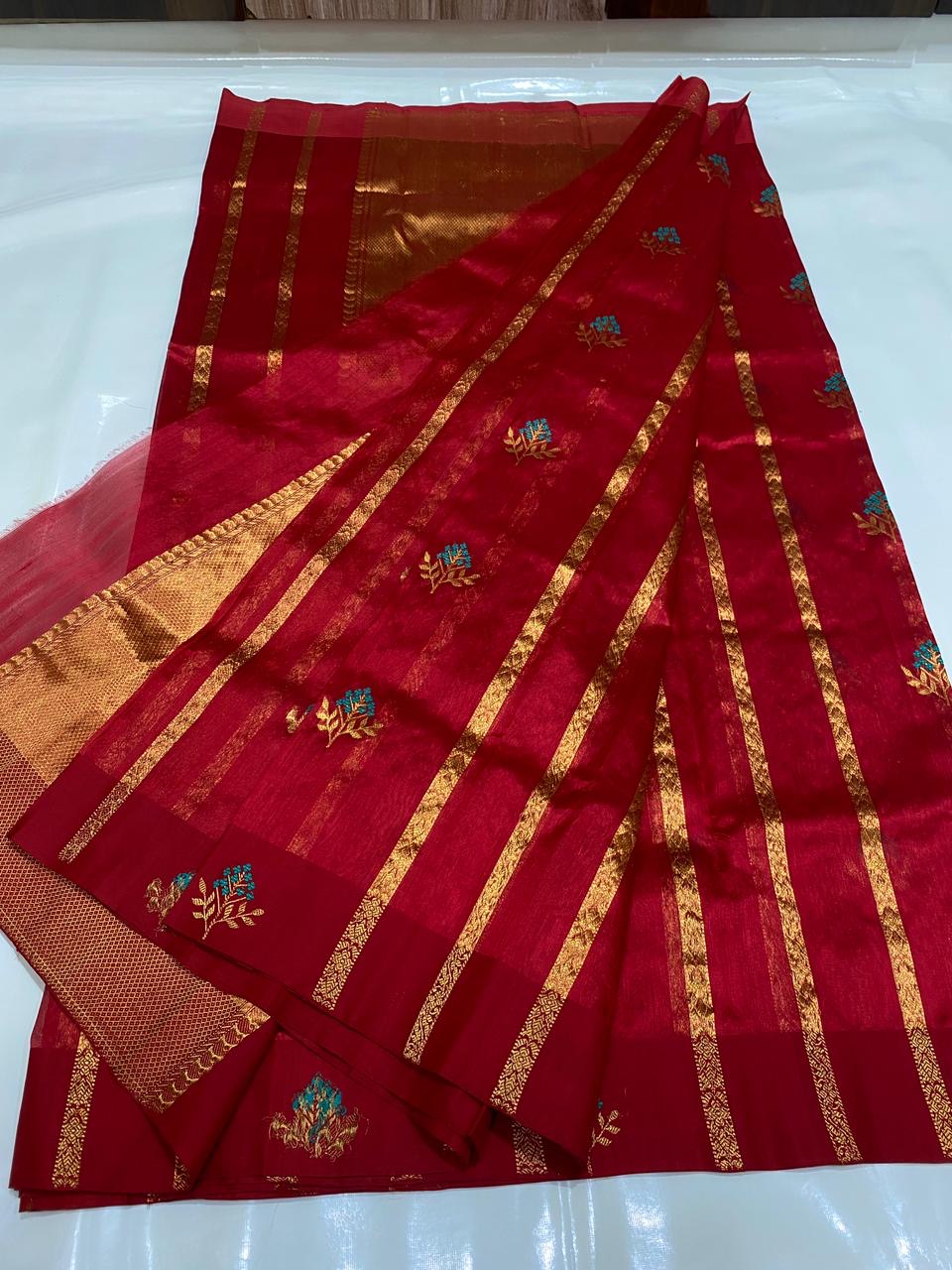 Raspberry red handloom Pattu Silk Chanderi saree folded with turquoise floral buttas and fine gold-toned zari border