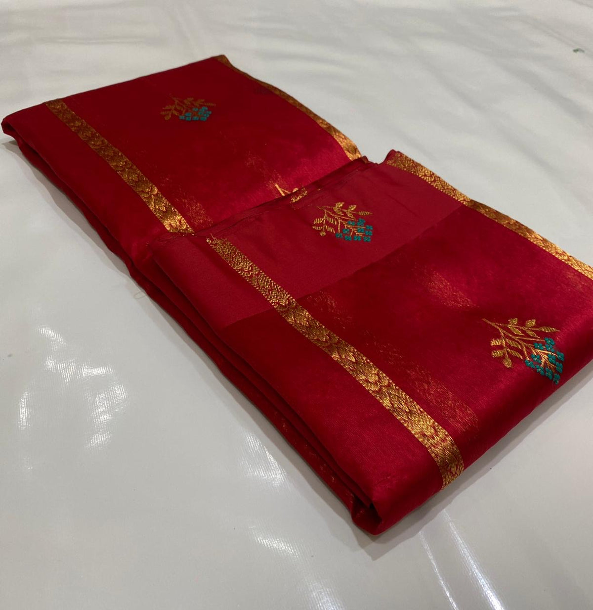 Draped raspberry red handloom Chanderi silk saree showing fine gold-toned stripes and turquoise floral buttas