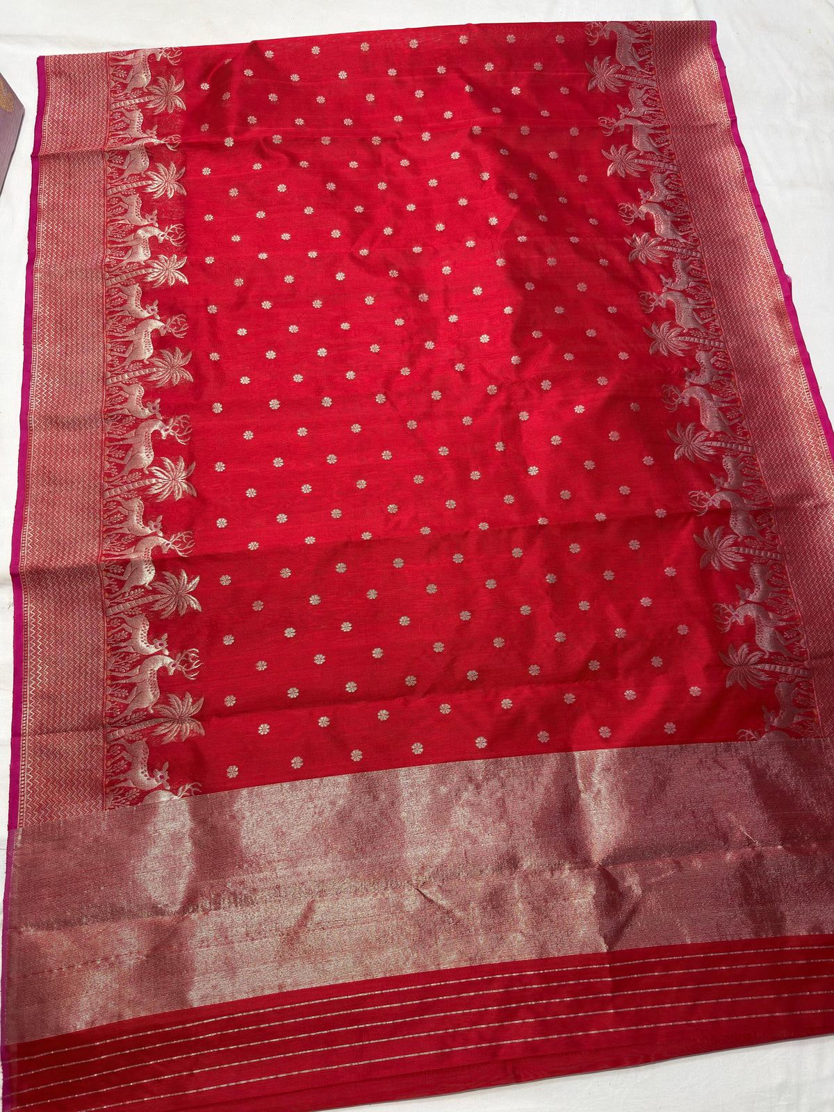 Detailed deer and palm-tree motifs woven along red Chanderi border