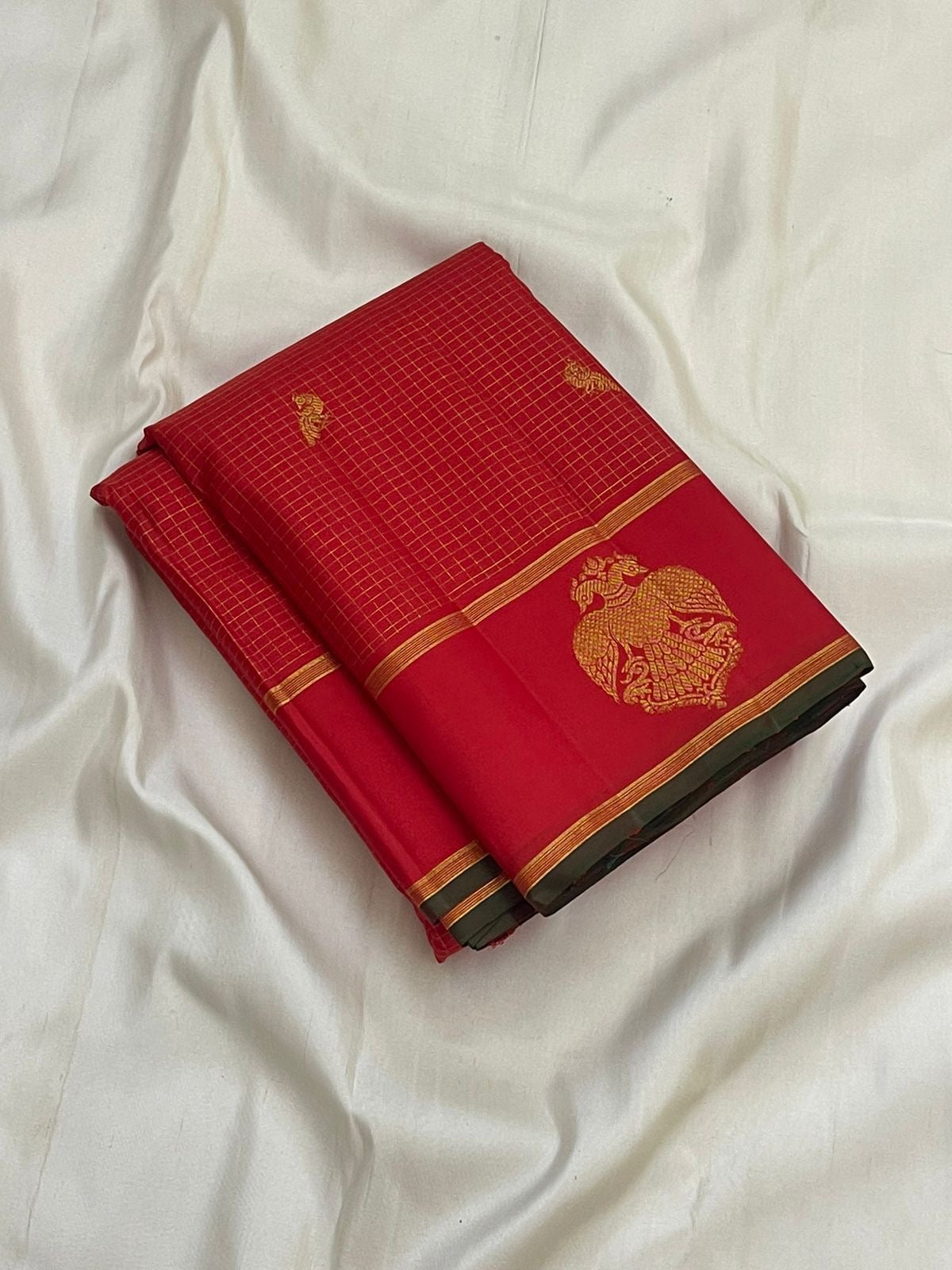 Folded red checked pure Kanchipuram silk saree with gold zari Gandaberunda motif and green edge border