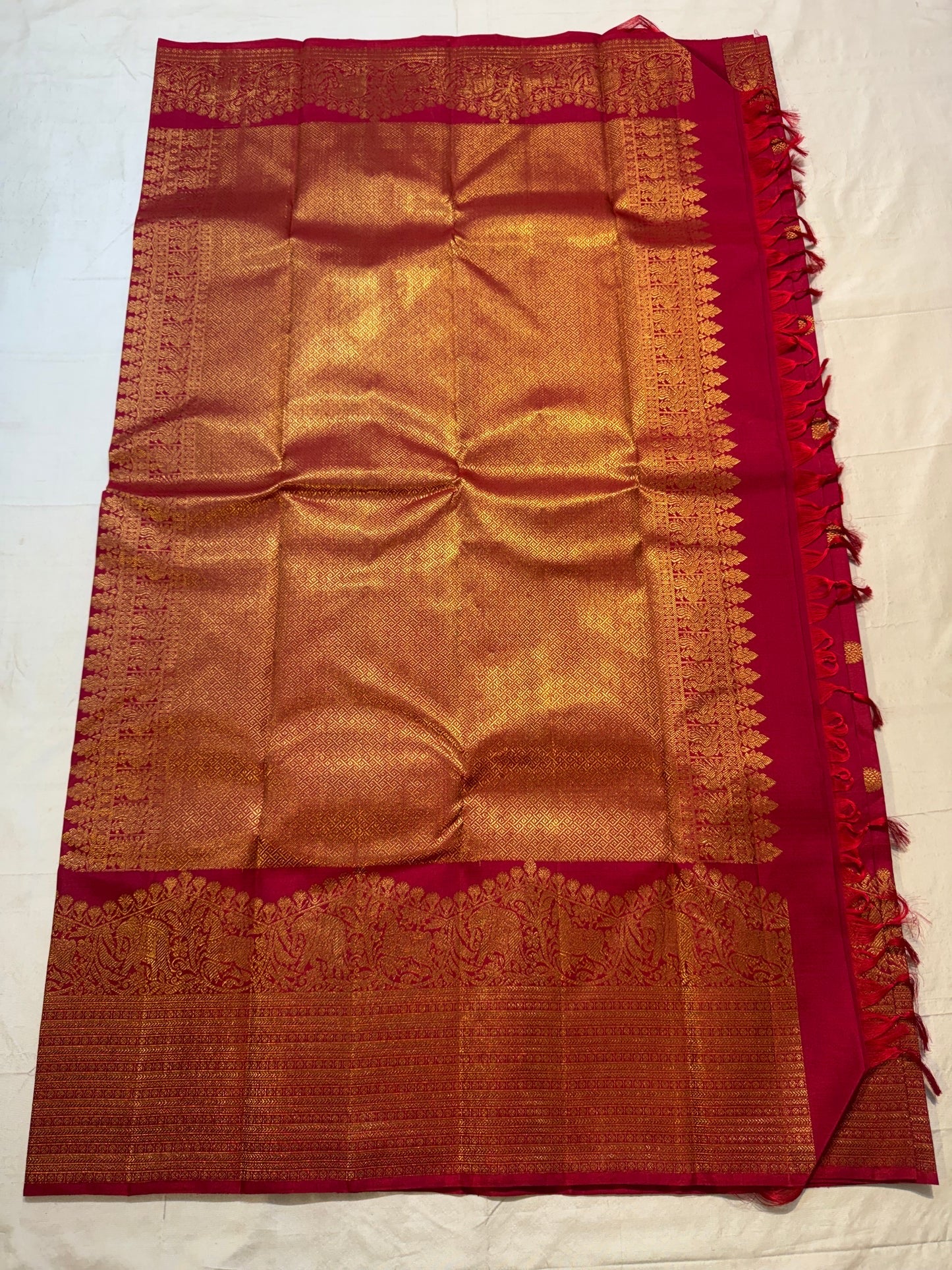 Open Red Deep Pink Pure Silk Kanchipuram saree showing richly woven gold zari pallu and ornate Vintage Turning Border.