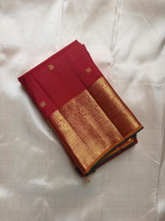 Deep red Kanchipuram silk saree spread flat showing antique gold zari border and pallu section