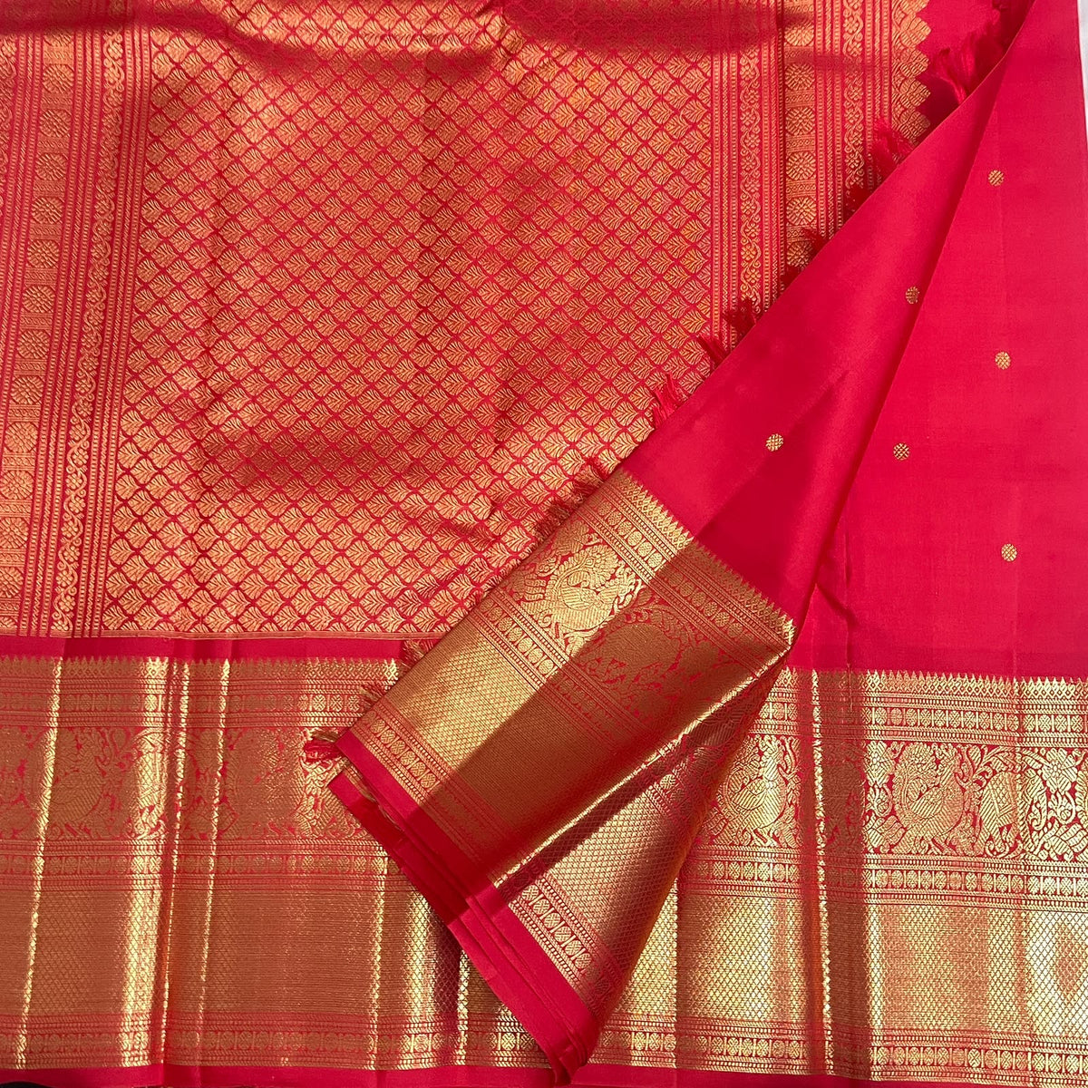 Close view of petite handwoven zari buttas across radiant Vermilion Red Kanjivaram silk.