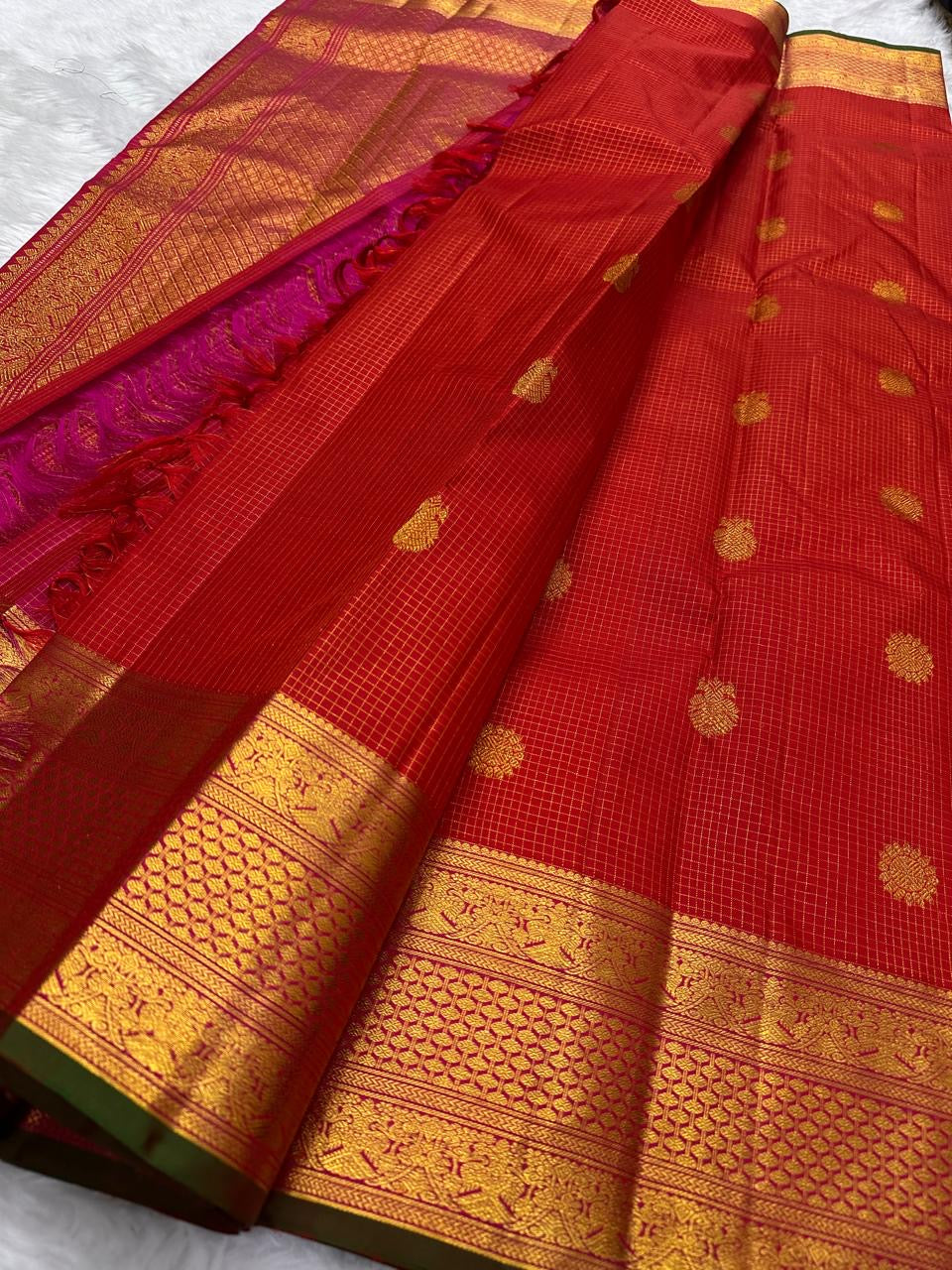 Red checked Kanchipuram silk saree with gold butta motifs and zari woven border, pallu visible in pink