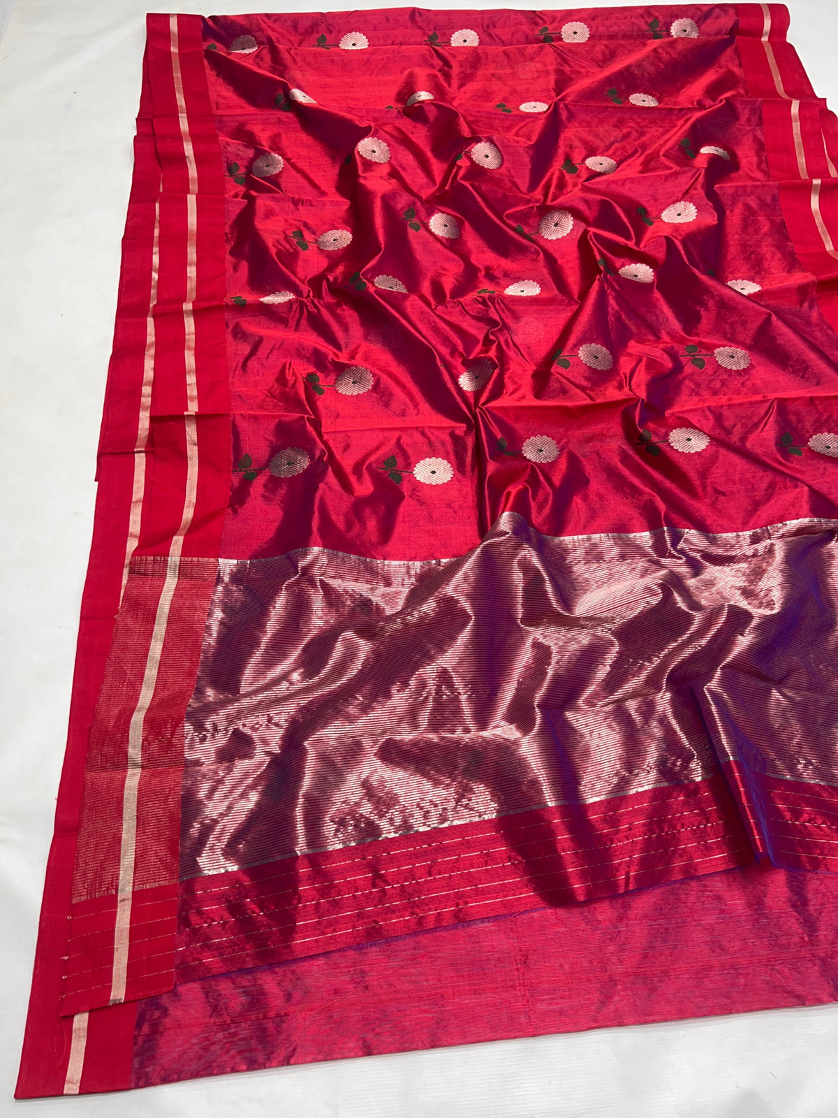 Close view of Raspberry Red Chanderi saree showing silver round floral motifs with deep green stems and leaves