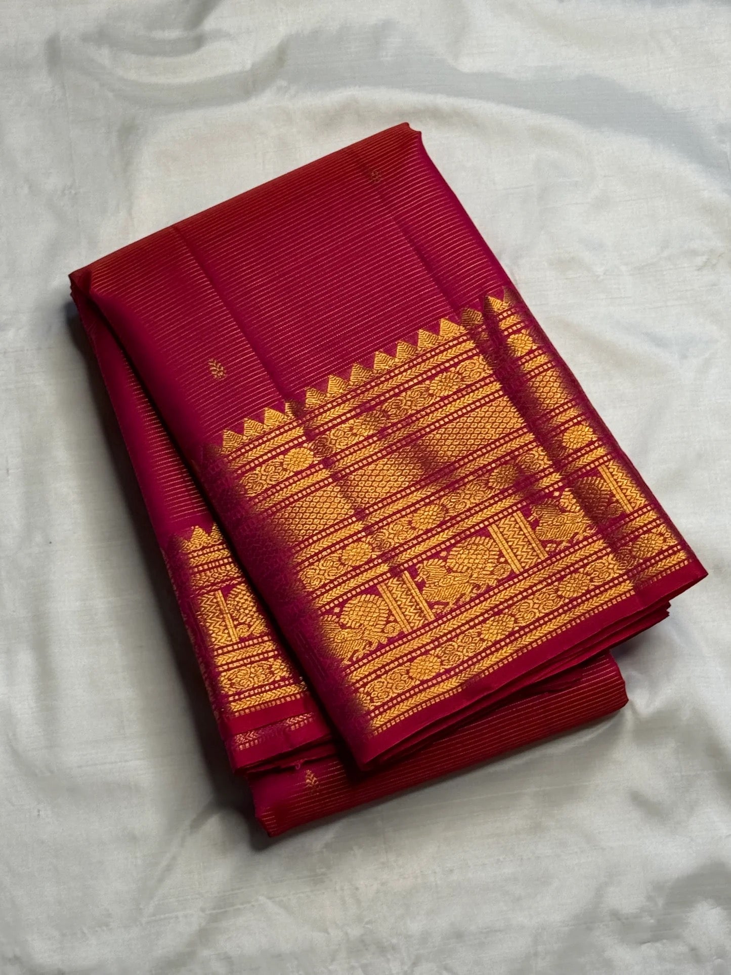 Close view of needle-fine gold Vairaoosi lines across vivid red-pink pure silk.
