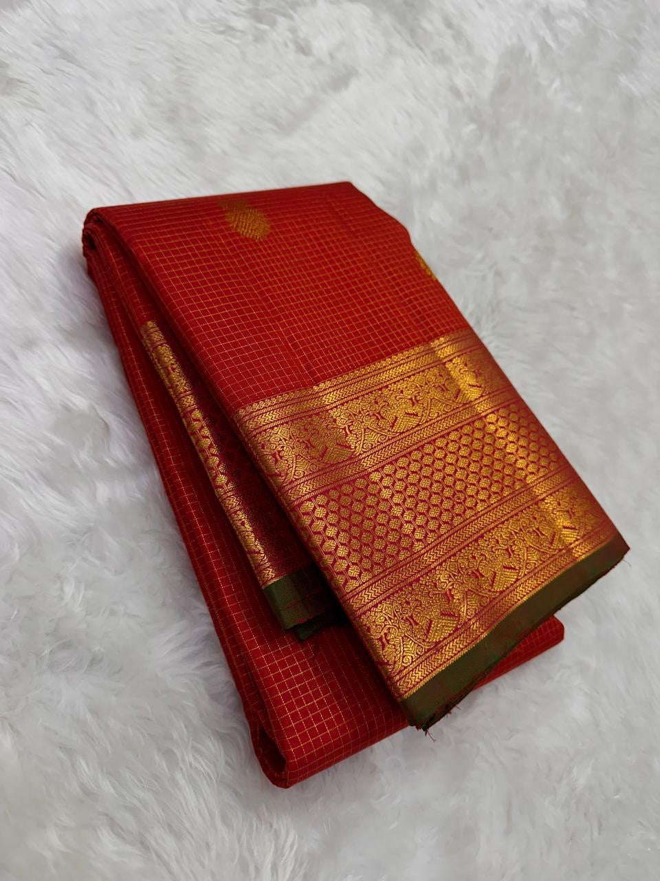 Folded red oosi kattam Kanchipuram silk saree with zari woven border and green edge, available in the USA