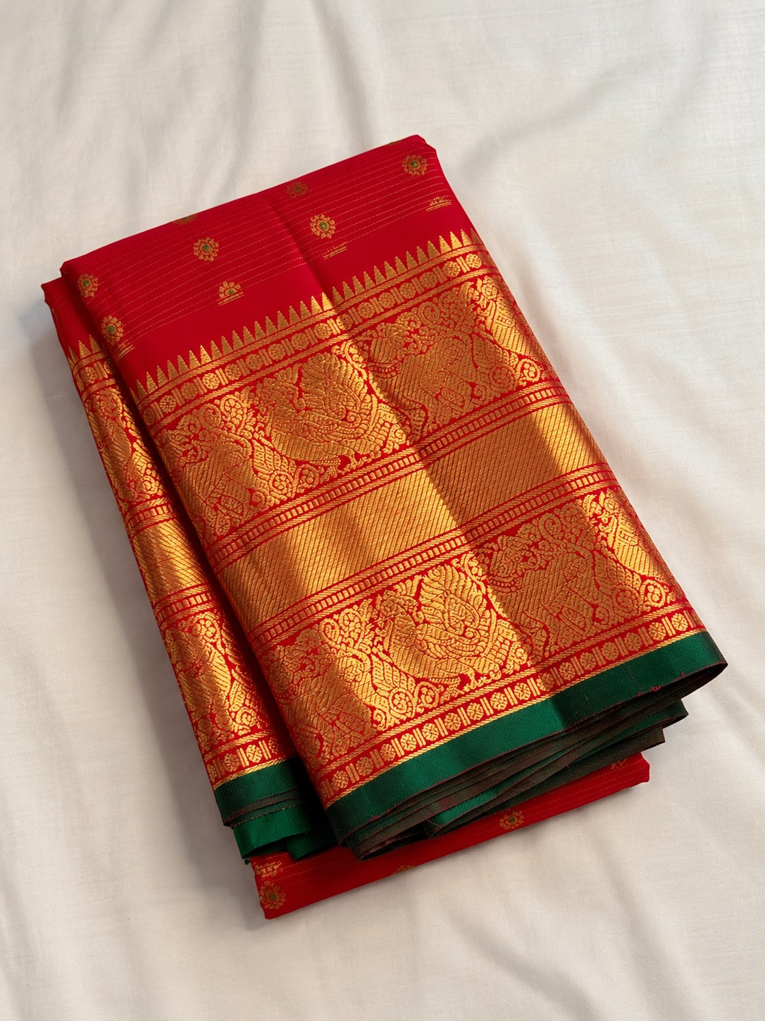 Red handwoven Pure Silk Kanchipuram saree with green-thread Meenakari Kamalam buttas, gold zari border and green selvedge, folded silk detail
