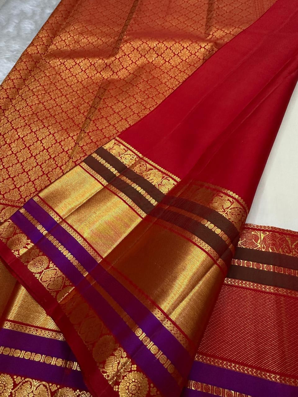 Angled full drape of ivory Pure Kanchipuram silk saree highlighting the wide gold zari border and red pallu panel beside the ivory body.