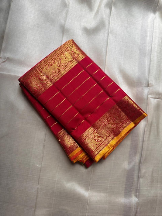 Pure Kanchipuram silk saree in deep red with zari kattam, folded view highlighting antique gold zari border