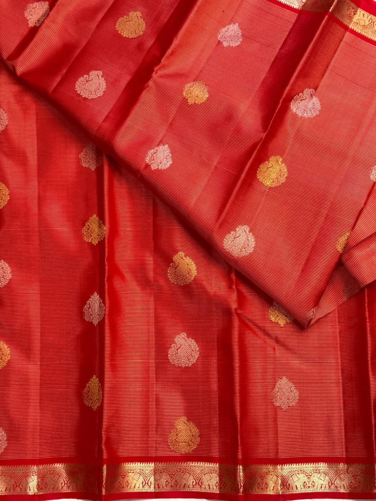 Red and gold pallu displaying repeated paisley shapes within a densely woven zari lattice grid
