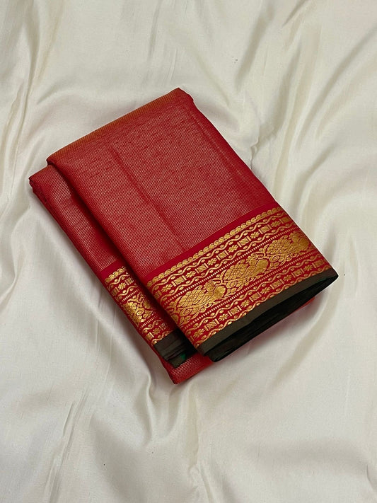 Folded vairaoosi red Kanchipuram silk saree on white fabric with gold zari border and forest green edge.