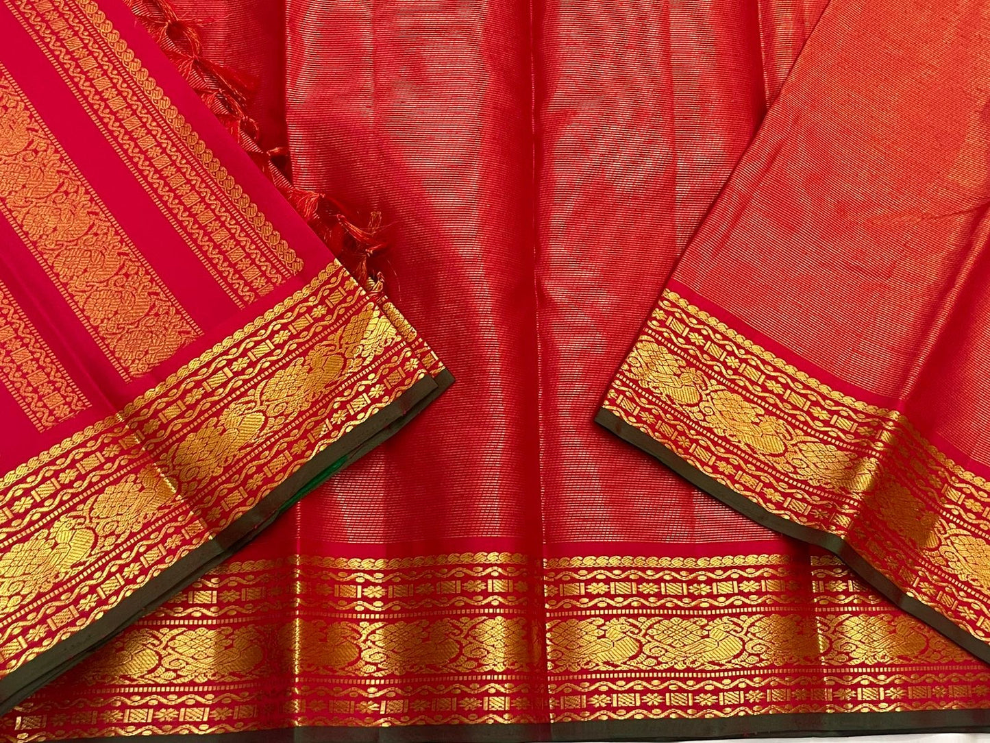 Red Kanchipuram silk saree body beside striped pallu panel, highlighting gold zari border and dark green edge.