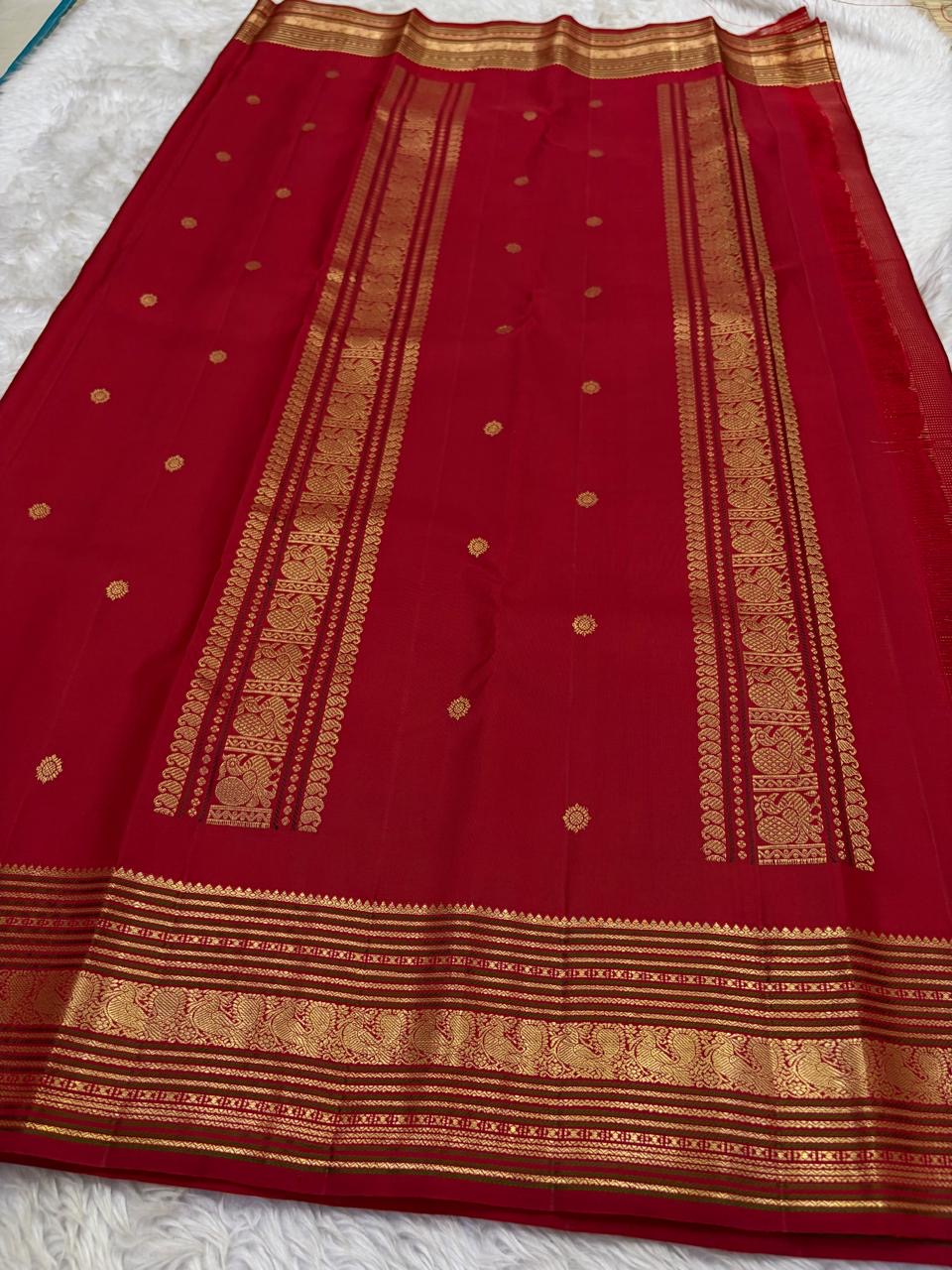 Pillar red Kanjivaram saree folded flat displaying varisaipet border with peacock zari motifs Idam Living