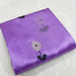 Folded lilac Chanderi Pattu silk saree with a close view of the white floral buti and dark leaf detail