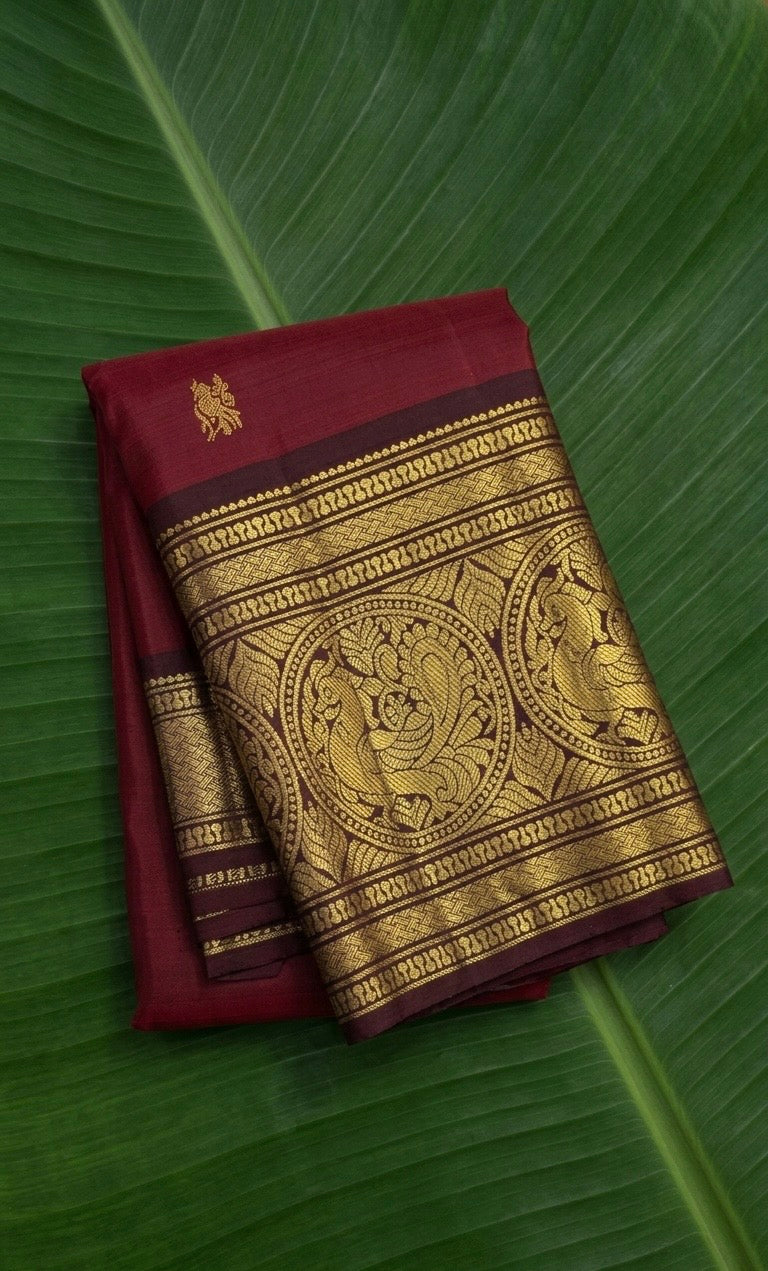 Rich burgundy red Kanchipuram silk saree with mayil motif zari border – front view