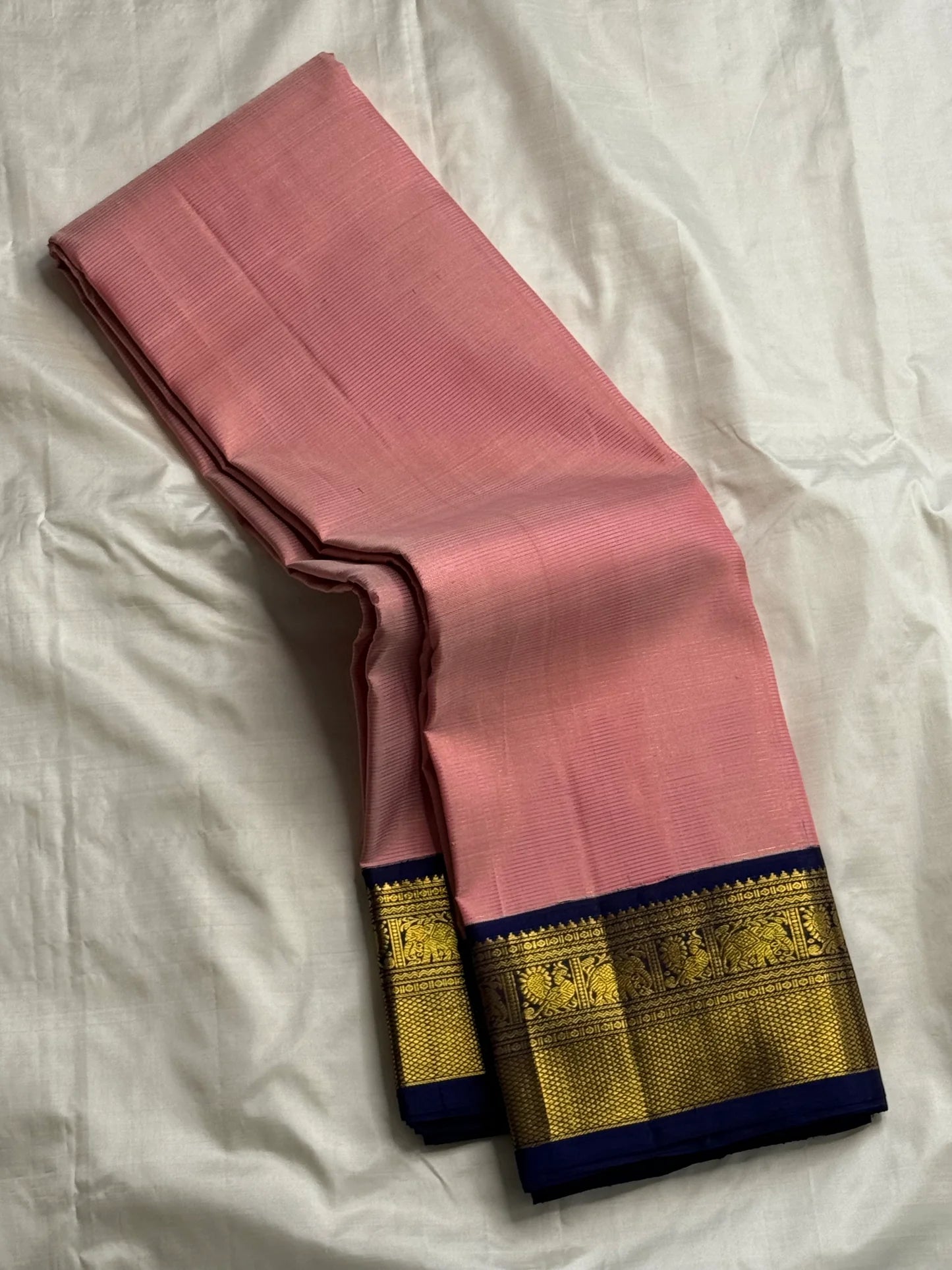 Rose pink Kanchipuram silk saree drape view showing fine self-striped texture and navy zari woven border
