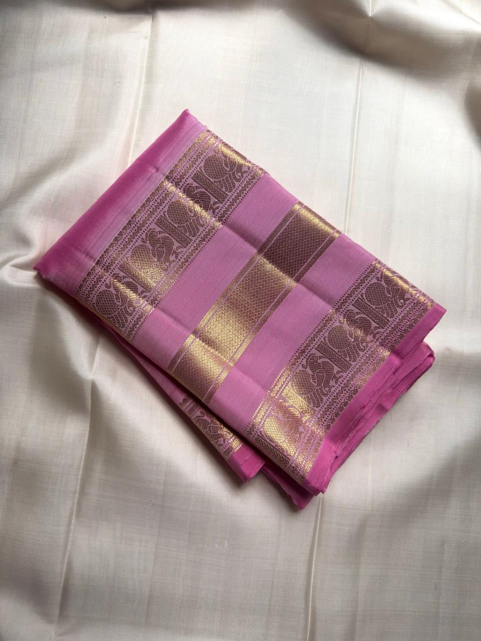 Folded Rose Orchid Pink Varisaipet saree showing traditional figurative gold zari border motifs.