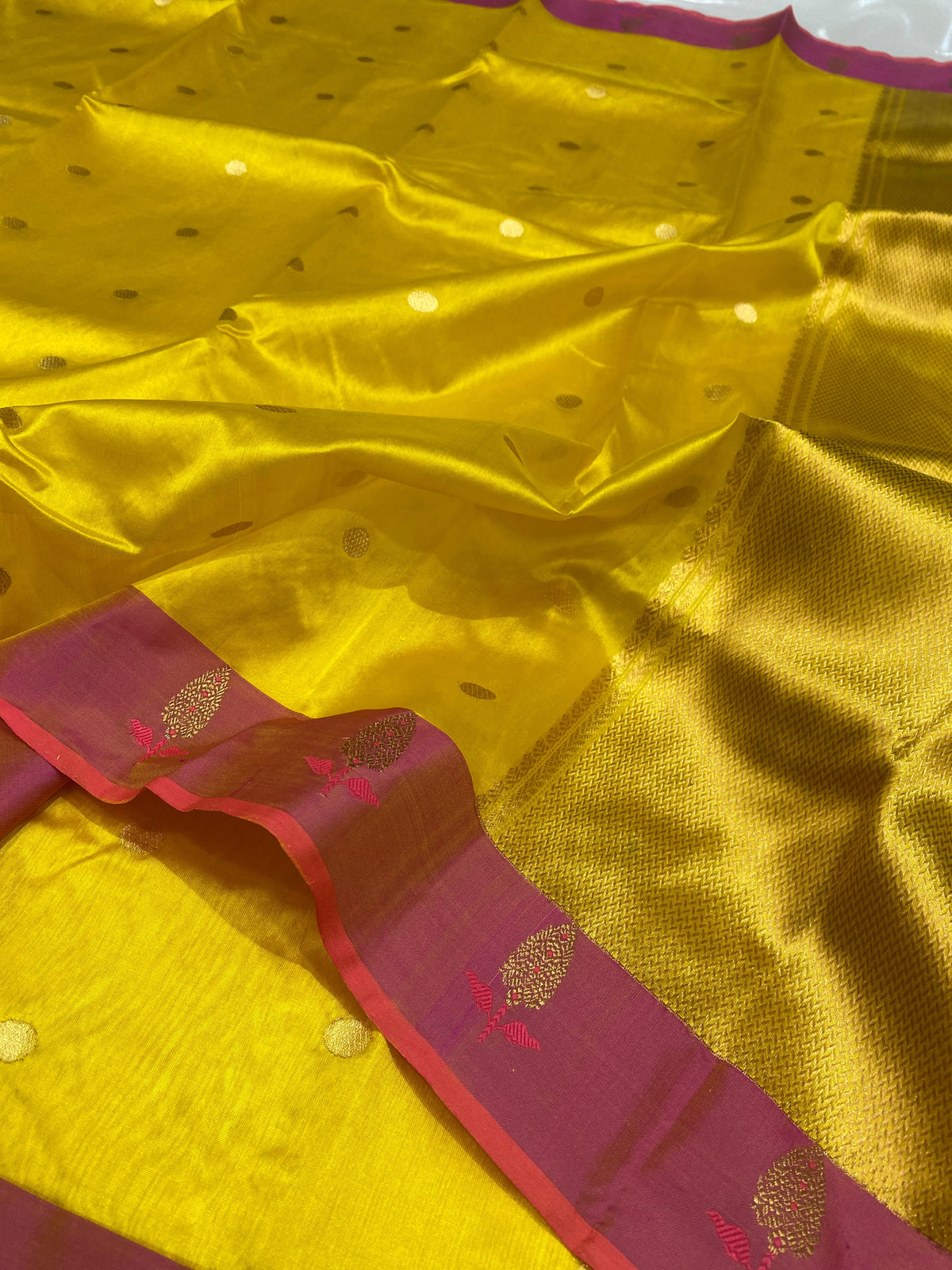 Turmeric yellow Pattu silk Chanderi saree showing gold-toned buttas, raspberry pink border and golden woven pallu