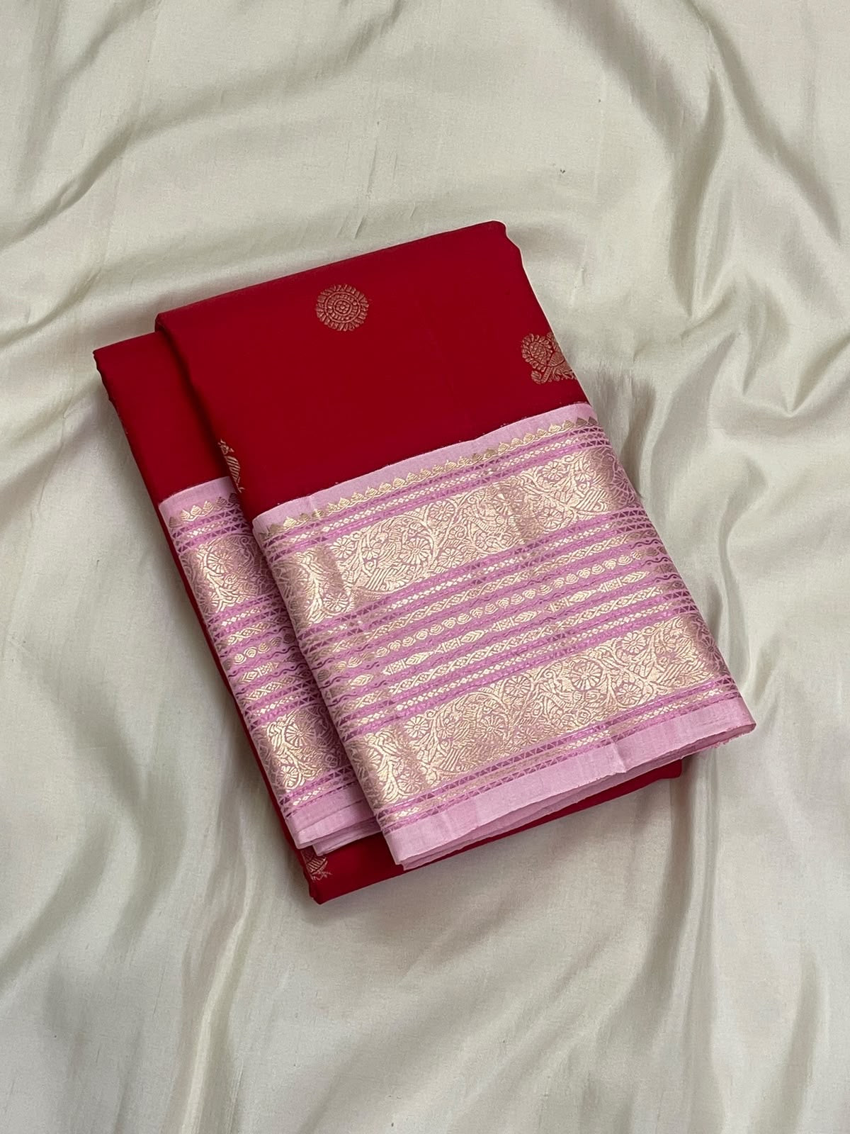 Handwoven crimson silk body showing regularly spaced circular zari medallions and stylised bird motifs.