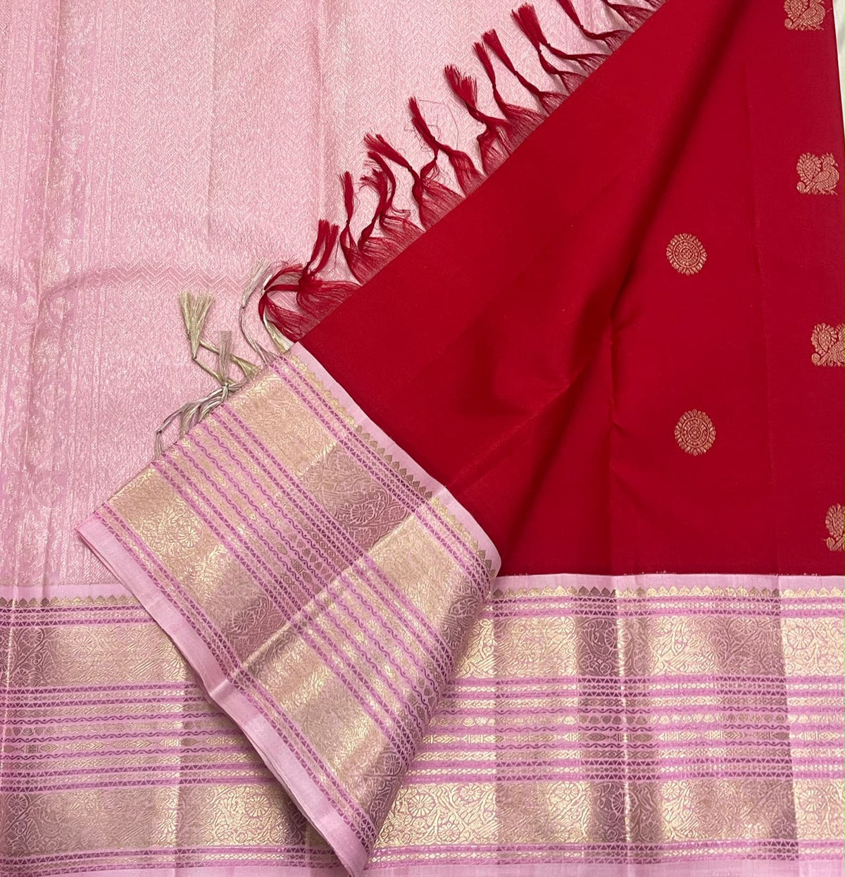 Crimson-red pure silk saree showing circular floral-geometric zari buttas across the body.