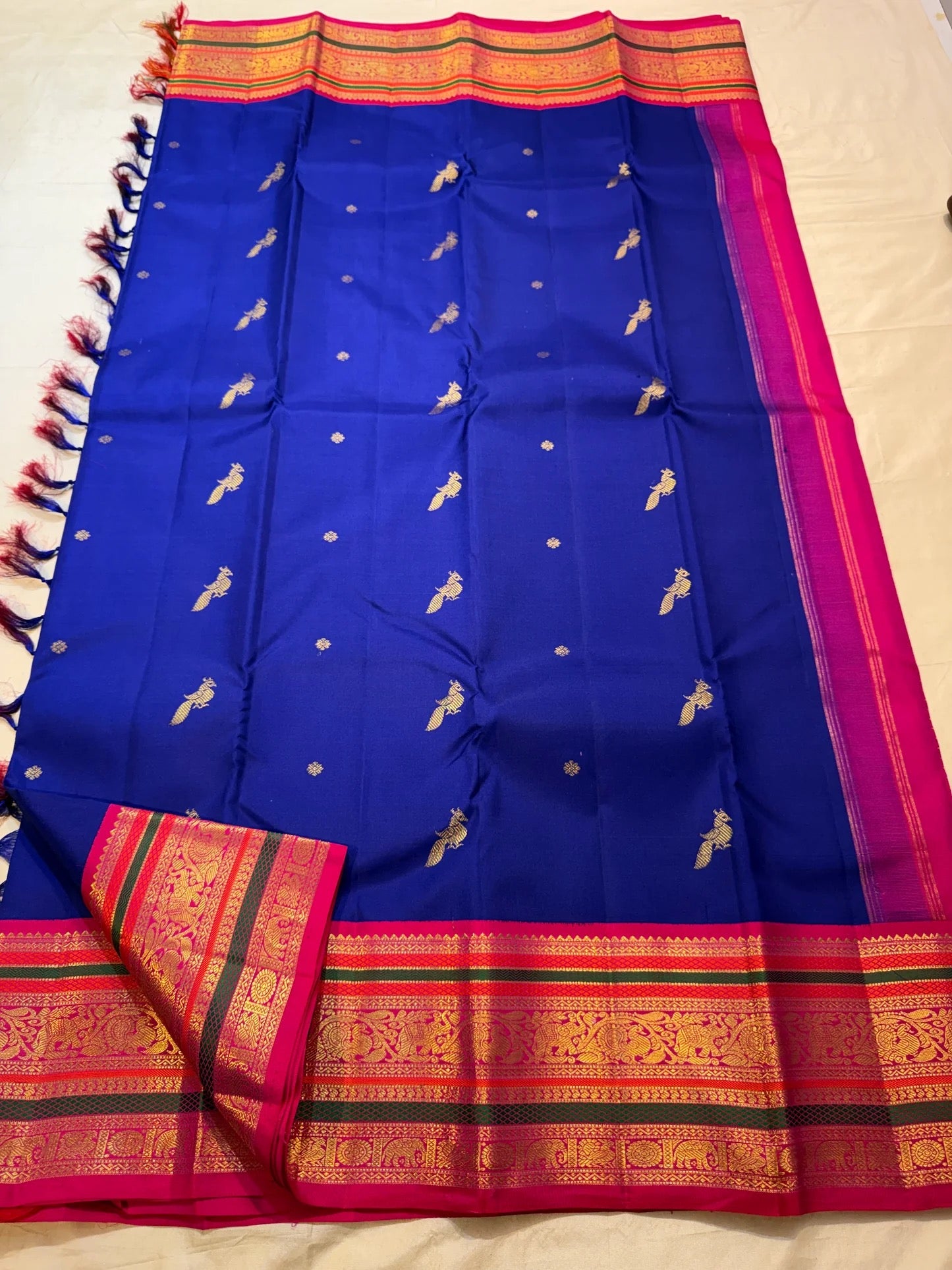 Folded Royal Blue Korvai silk showing vivid Rani Pink stacked border with green bands and gold zari.