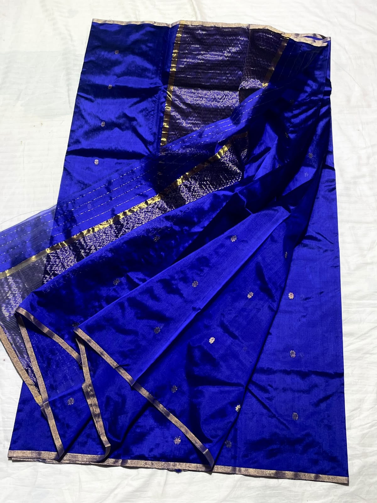 Folded royal blue Pattu Silk Chanderi handloom saree with small gold-toned buttas.