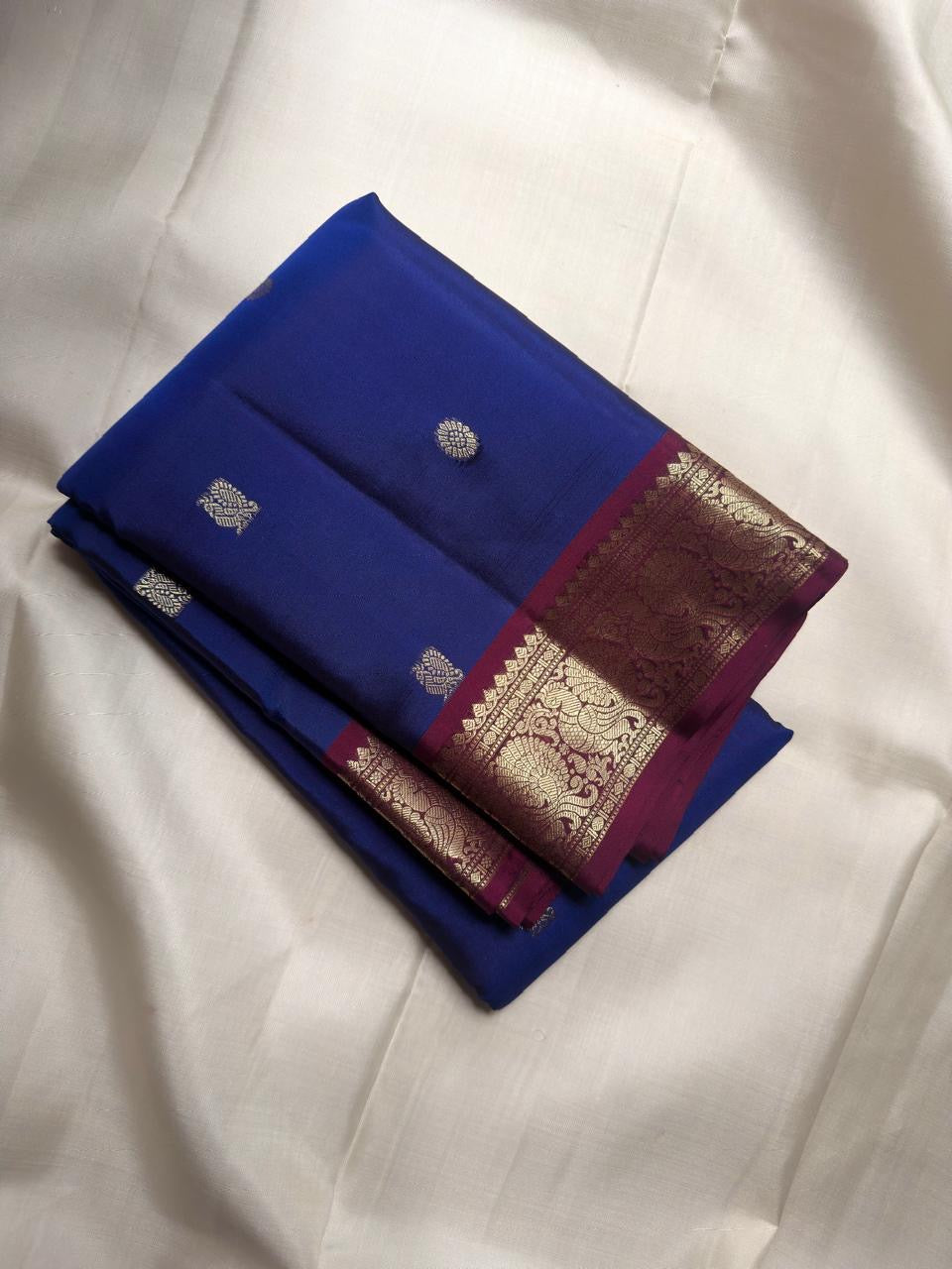 Handwoven Royal Blue Kanchipuram silk saree with antique-gold zari buttas and purple border.