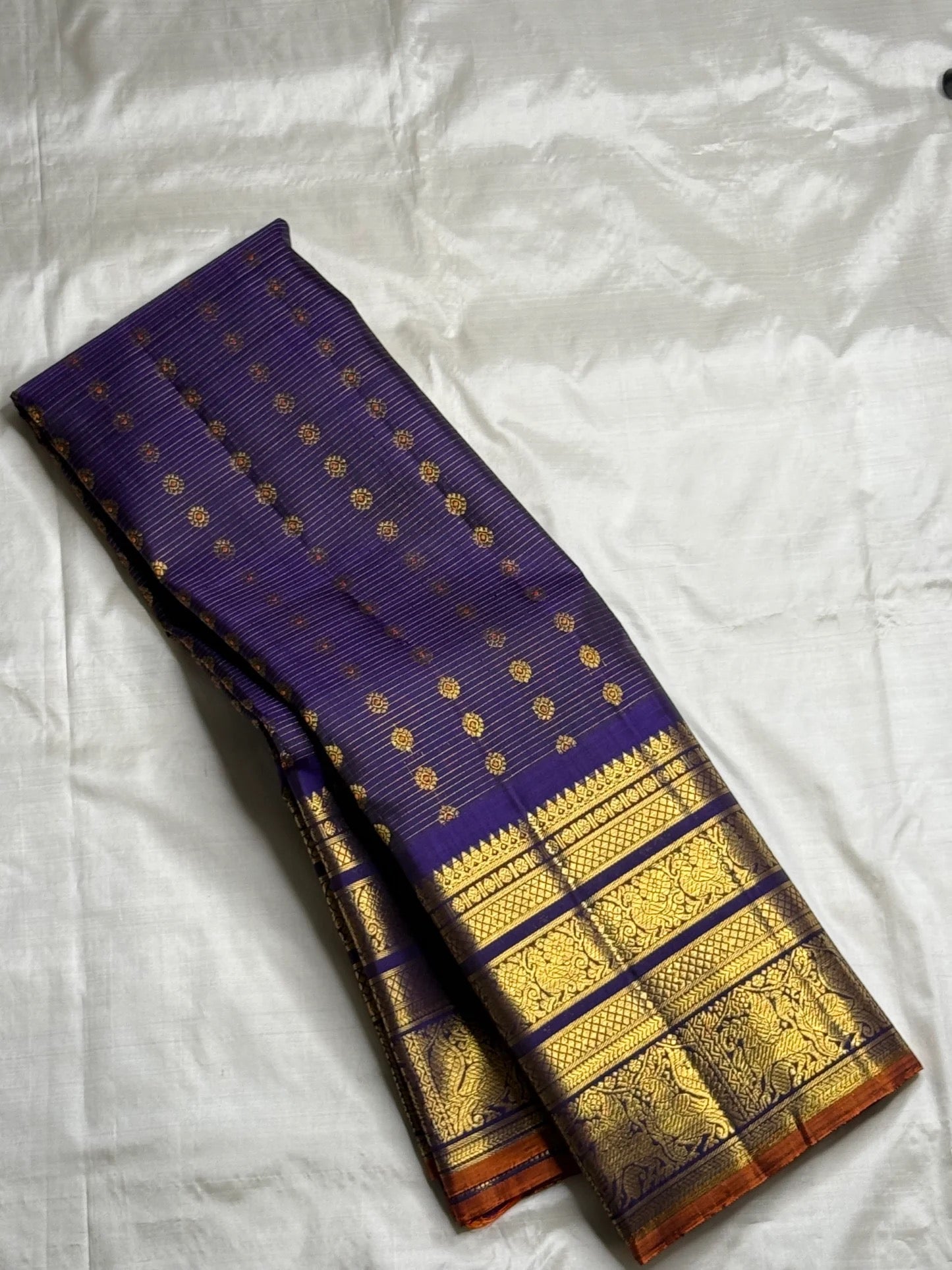 Folded body view showing fine zari lines and small circular gold buttas on Royal Indigo Violet silk