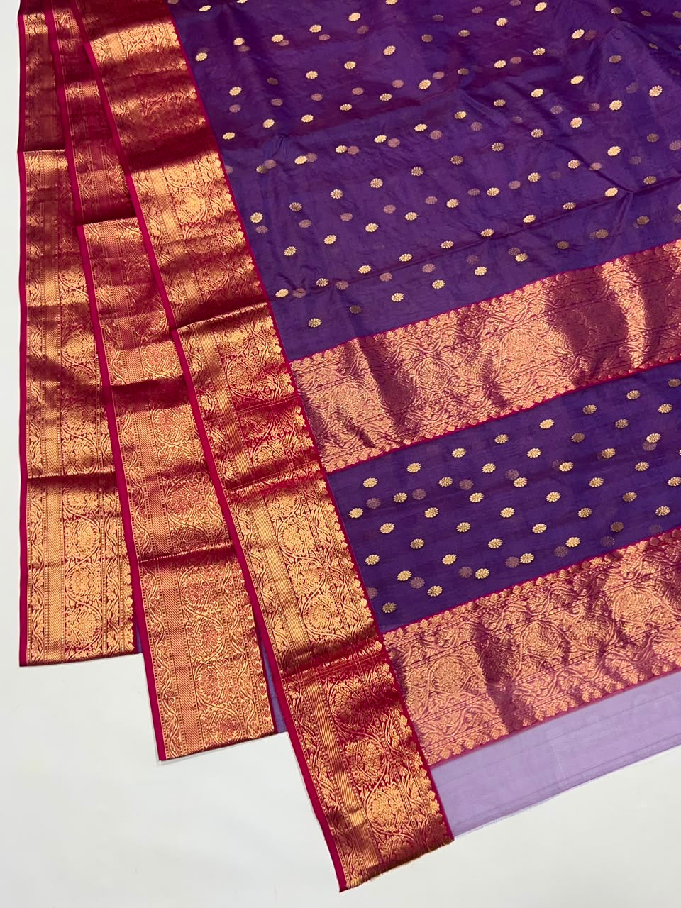 Draped Royal Purple handloom Chanderi showing gold floral buttas and broad decorative gold border framed in Rani Pink.