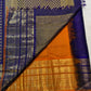 Folded violet Vairaoosi saree highlighting broad layered gold zari border and Burnt Orange finishing edge
