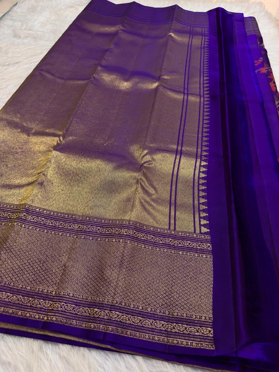 Purple Kanchi Pattu saree with large coral orange sage and gold handwoven floral motifs.
