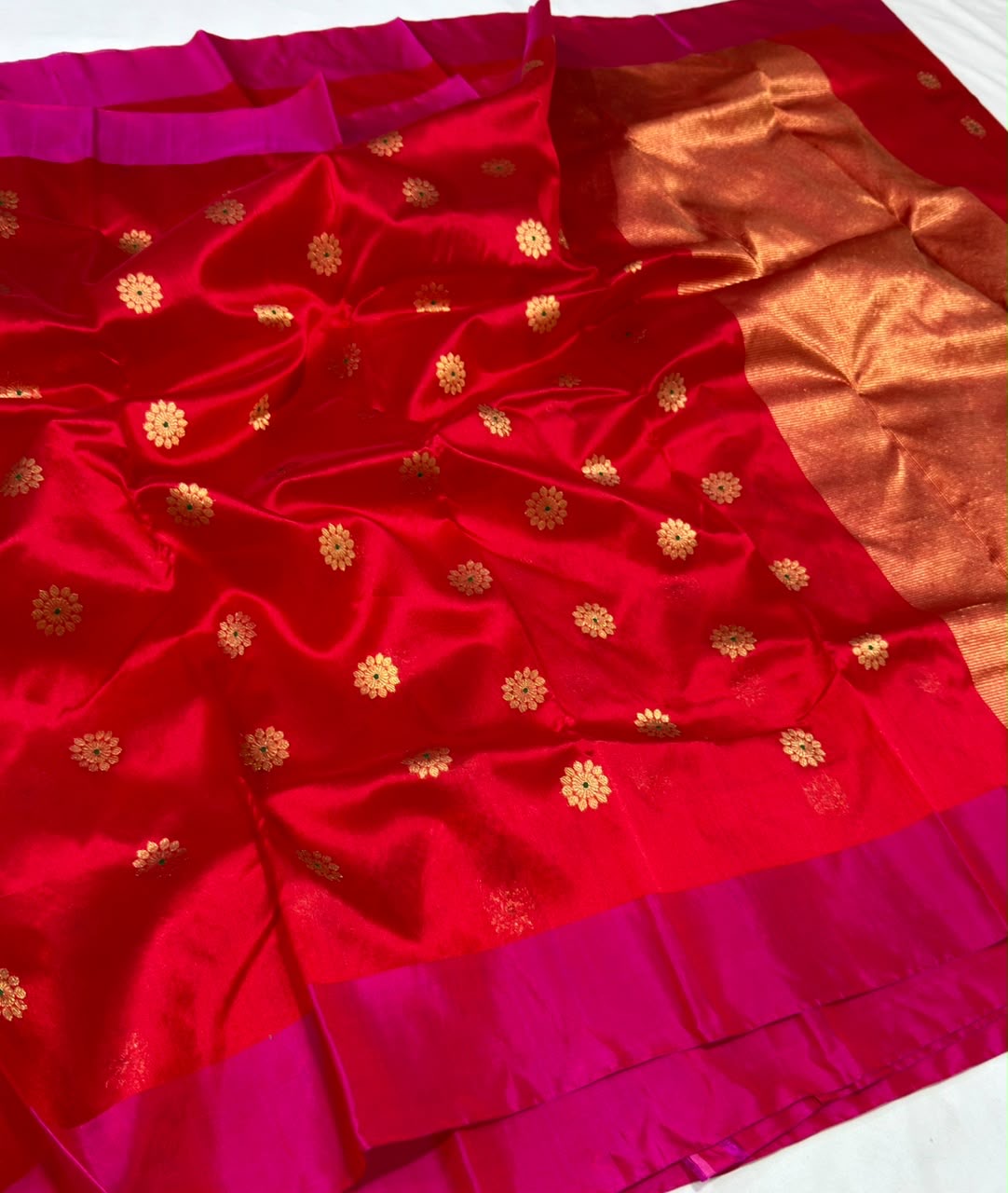 Open drape of ruby red Chanderi saree with gold-toned floral buttas and vivid pink borders.
